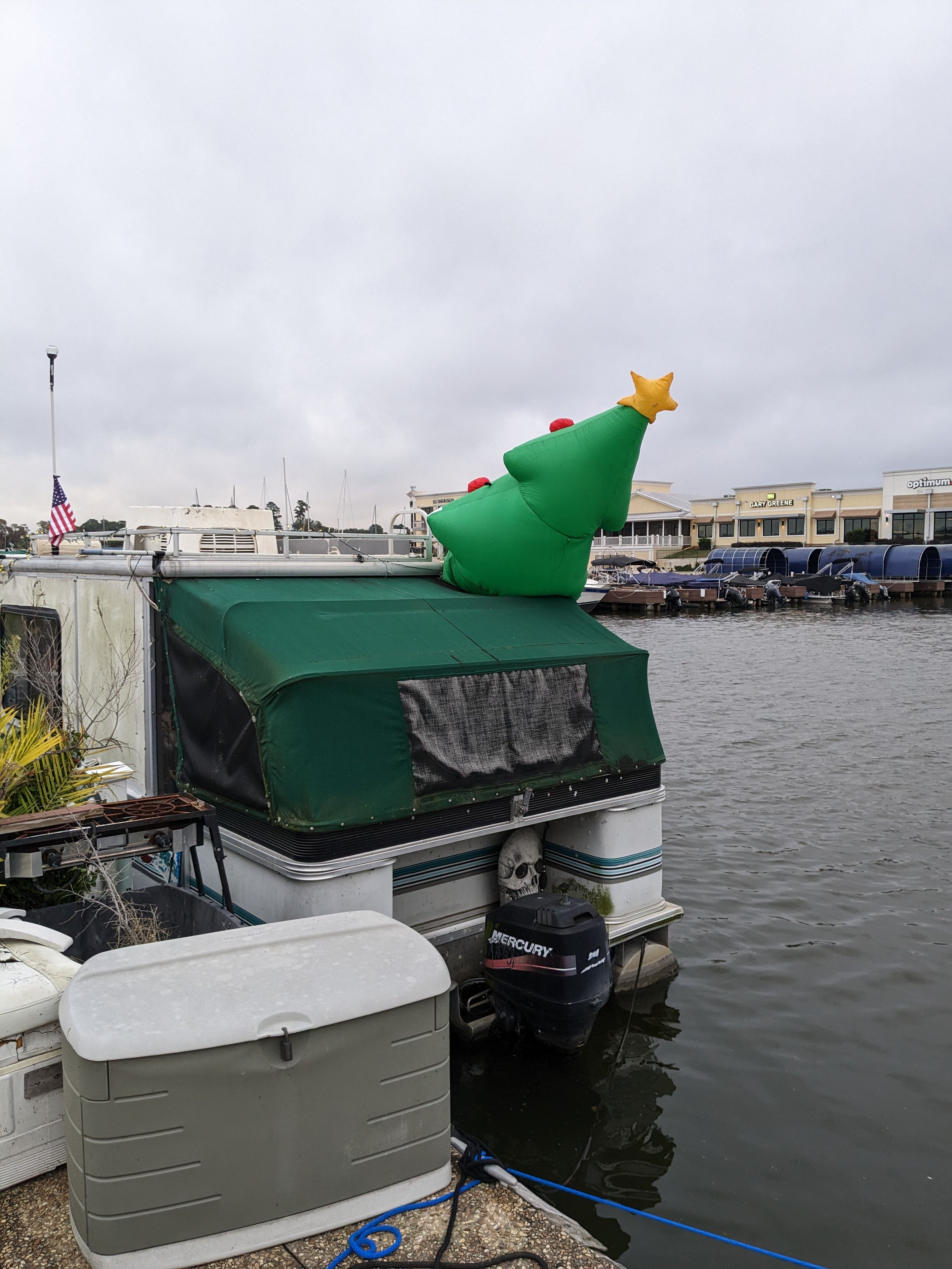 A boat with an inflatable Christmas tree on the roof, moored at a dock.