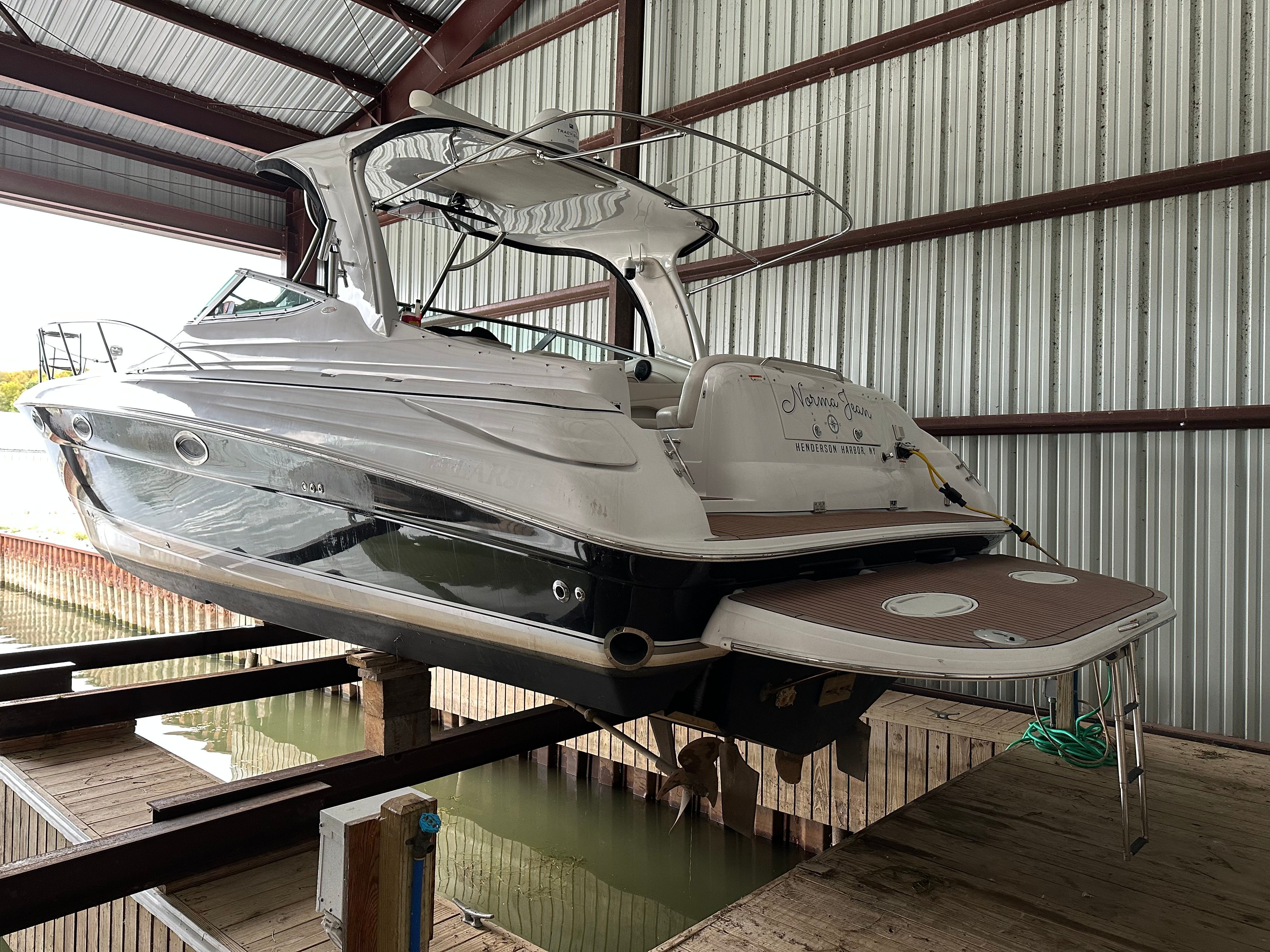 A white boat is hoisted in a covered dock area.