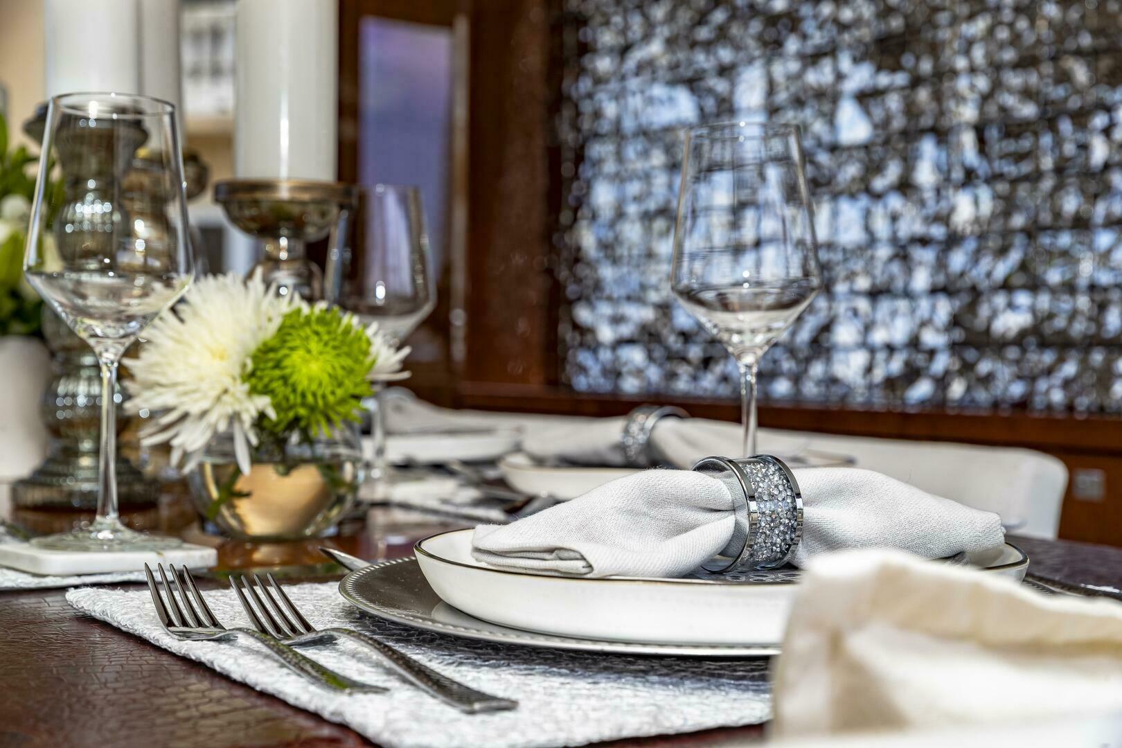Elegant dining setup on a 2012 Princess 32M yacht with fine tableware and floral centerpiece.