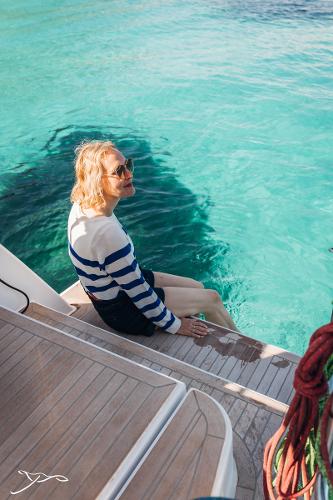Woman relaxing on a 2025 Nautitech 44 Open yacht by turquoise water.