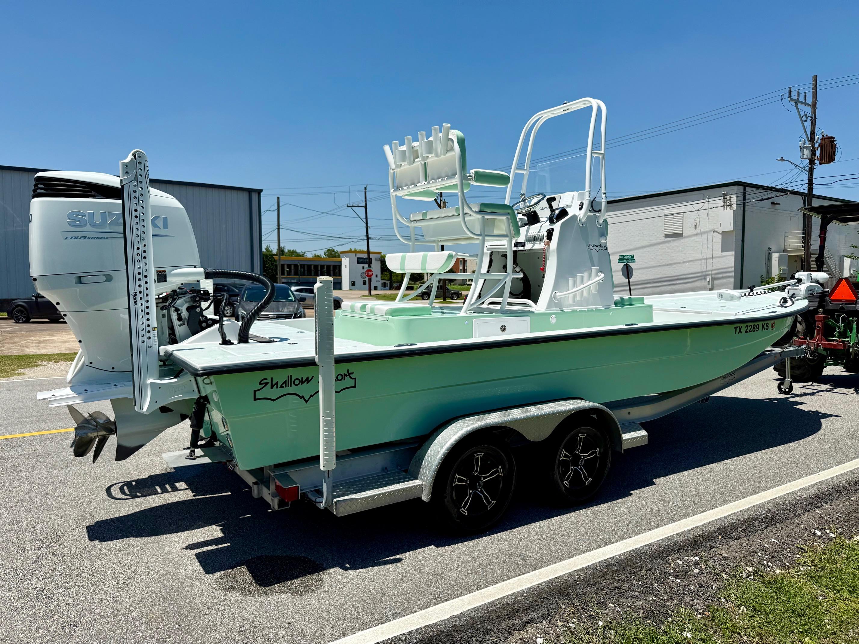 2023 Shallow Sport 24 Sport boat with Suzuki engine on a trailer, parked outdoors.
