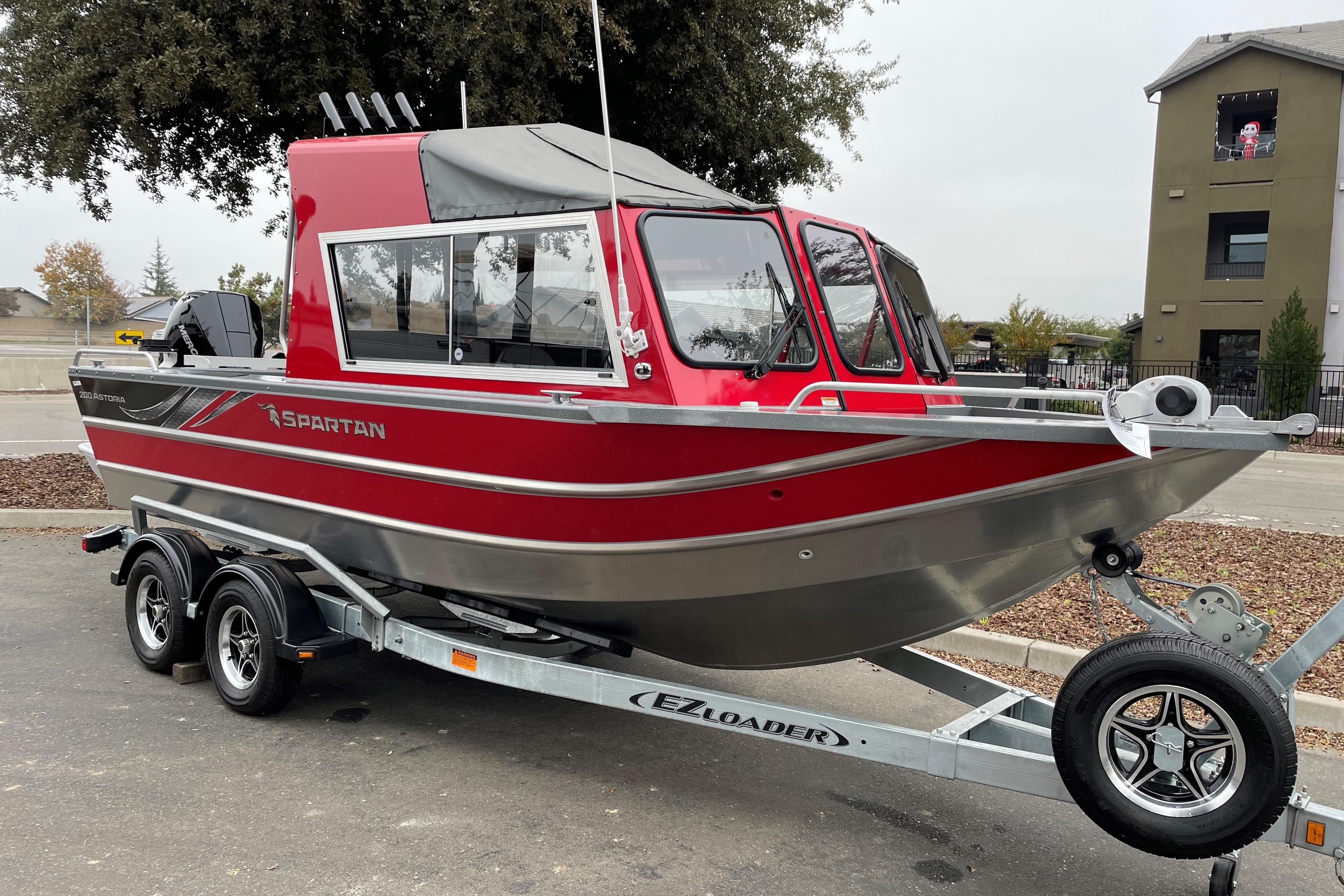 2024 Spartan 200 Astoria boat on trailer, red and silver design, parked outdoors.