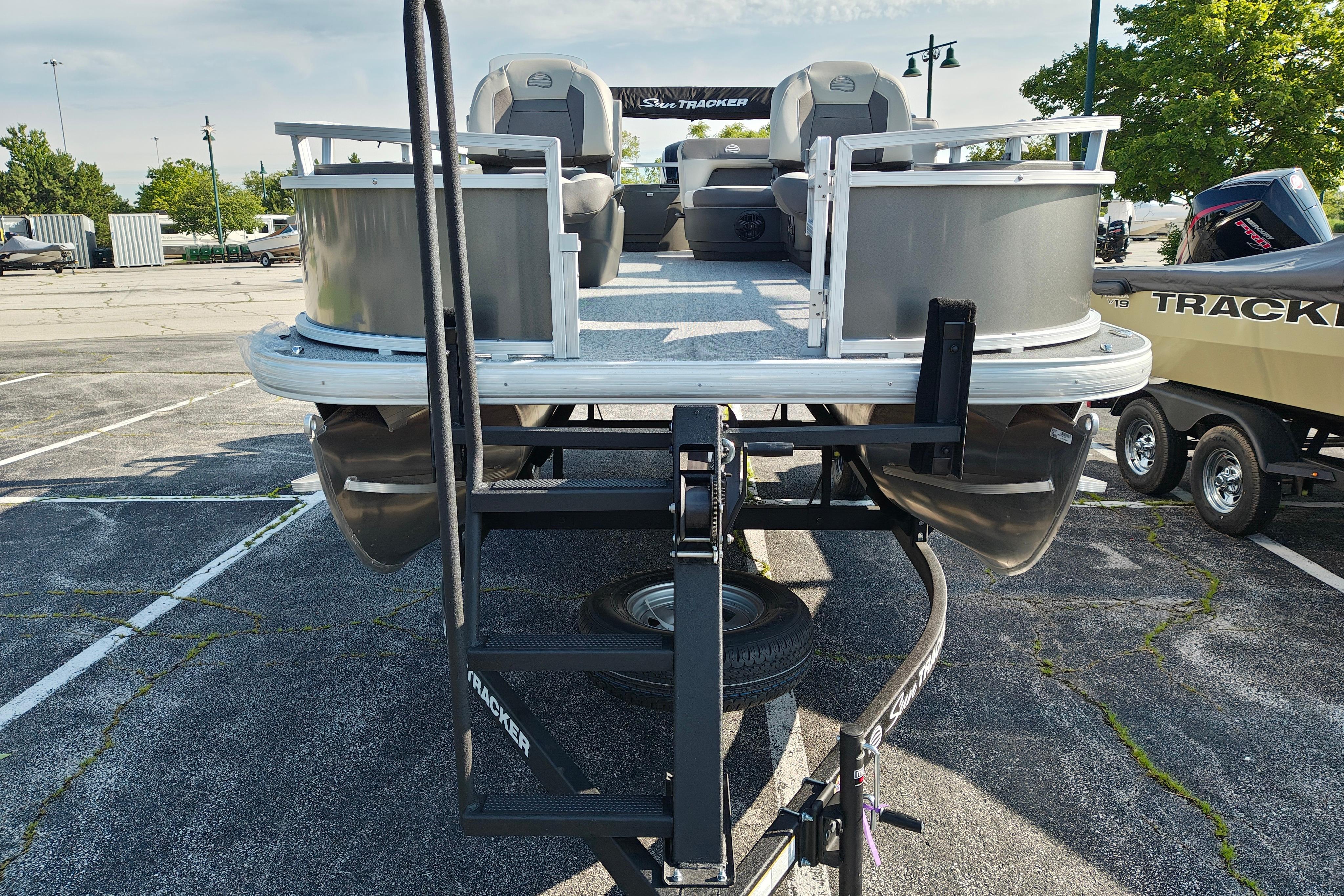 2026 Sun Tracker Bass Buggy 18 DLX pontoon boat on trailer in parking lot.