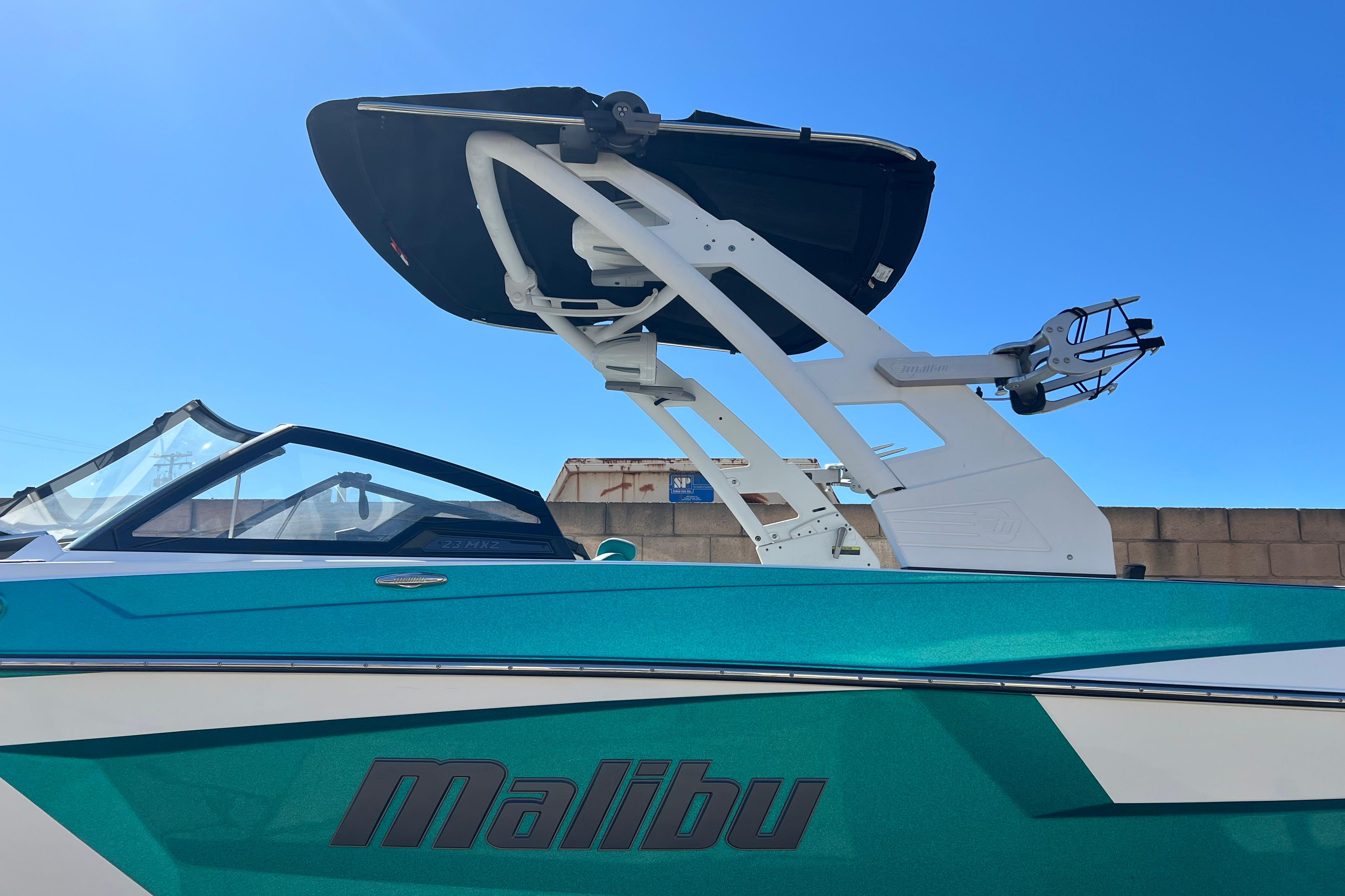 2020 Malibu Wakesetter 23 MXZ boat with teal and white design under clear blue sky.