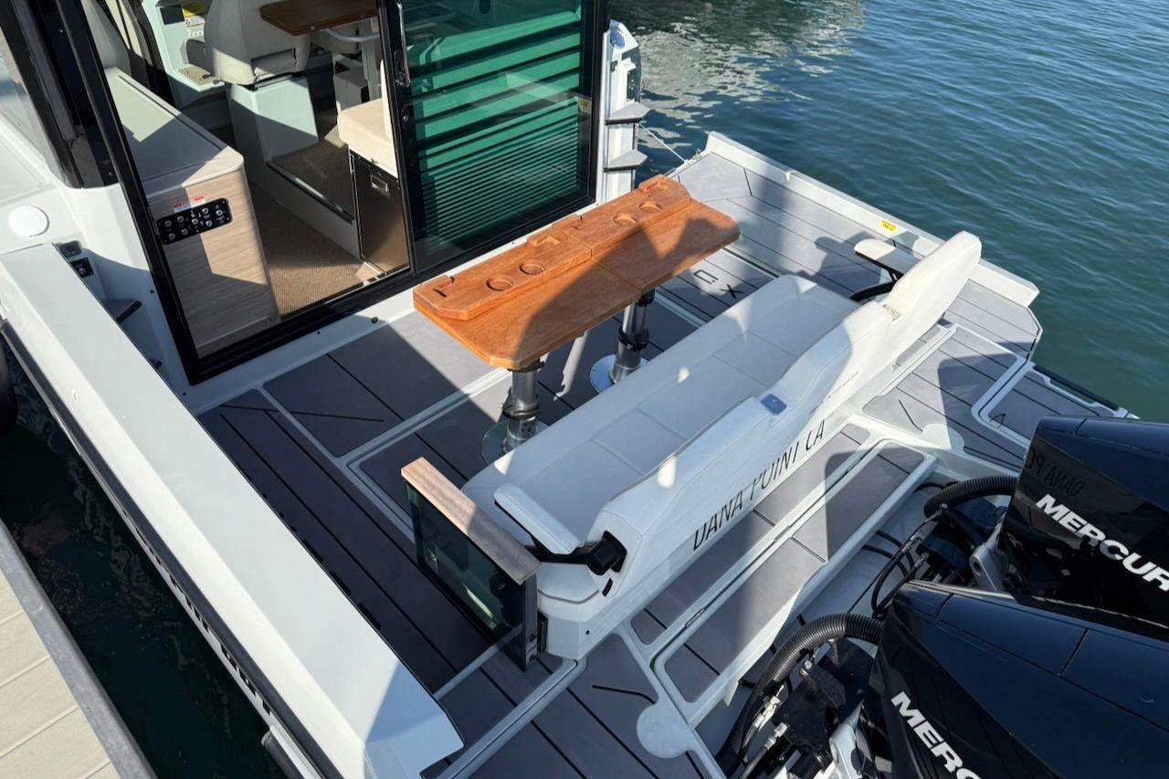 2024 Saxdor 320 GTC boat with seating area, wooden table, and dual Mercury engines.