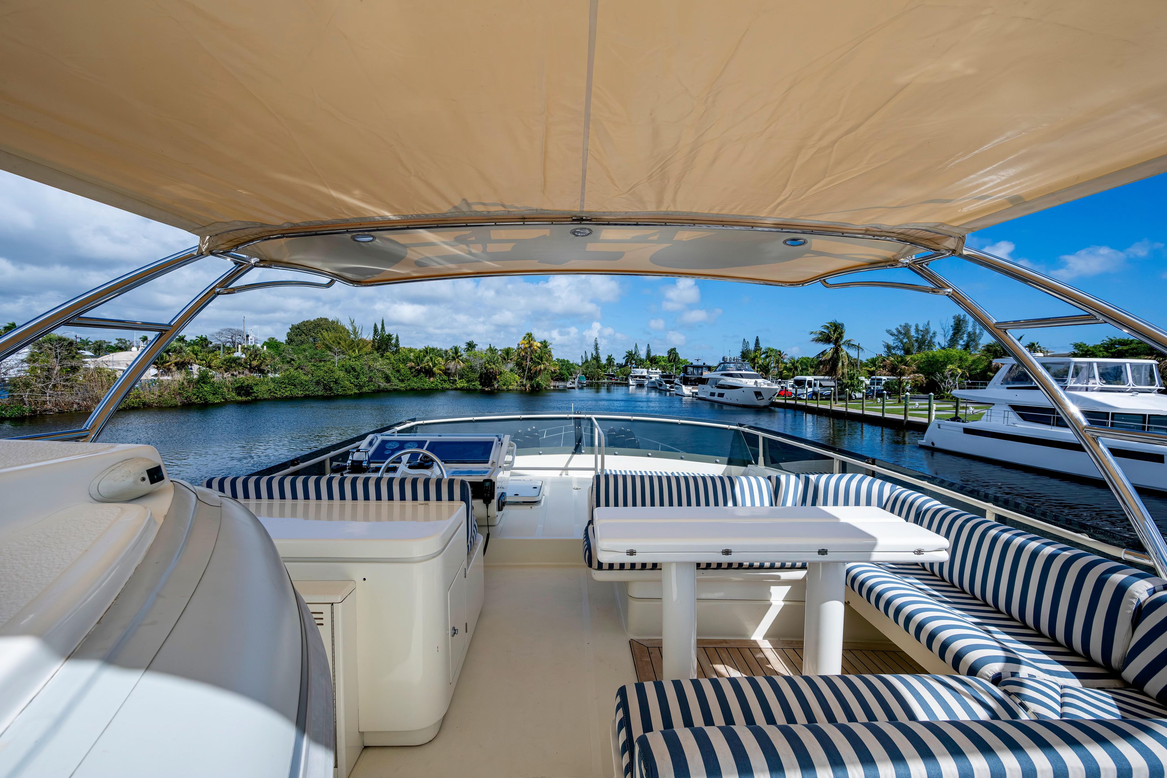 Luxurious 1997 Ferretti Yachts 650 with striped seating, cruising on a scenic waterway.
