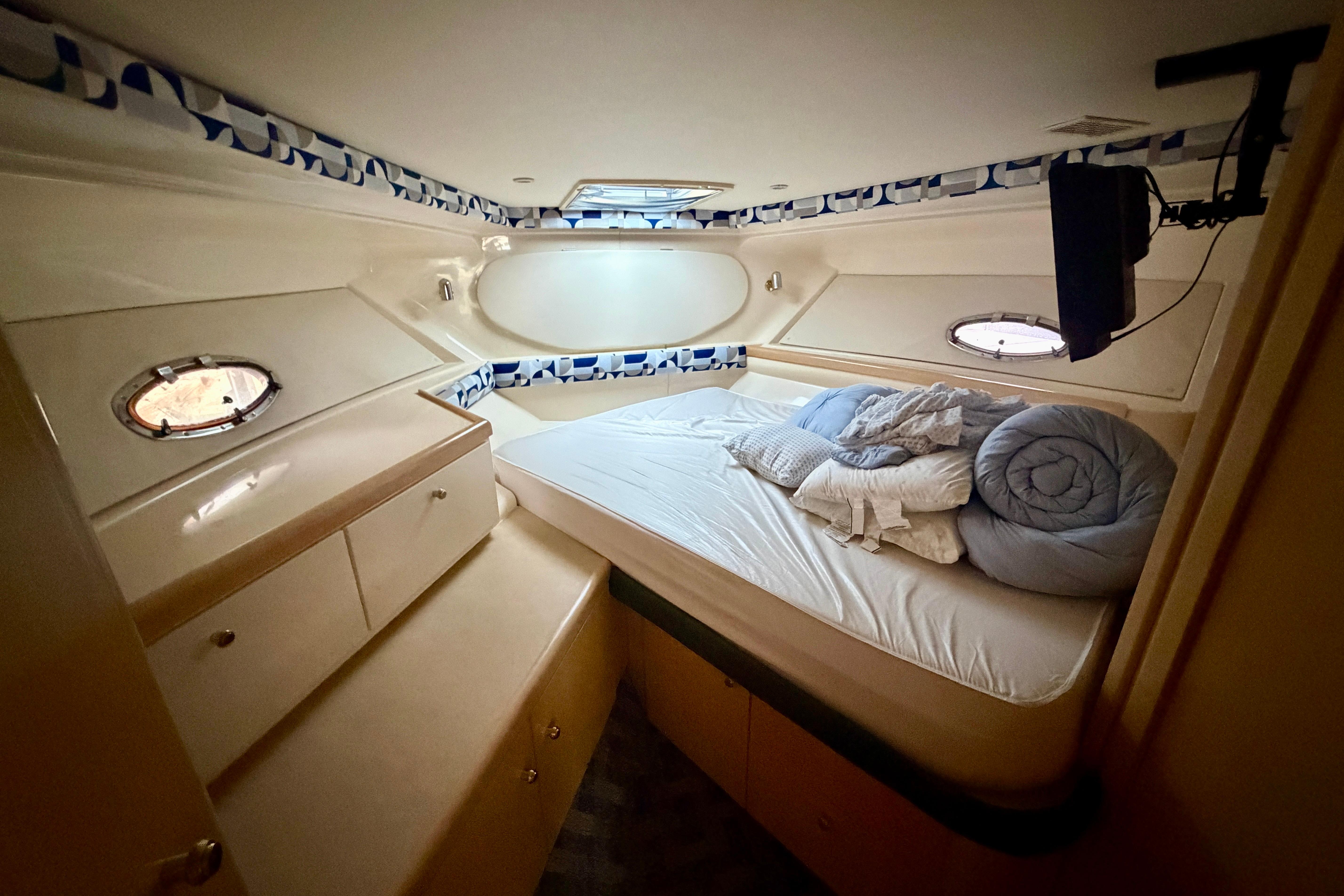 Cozy cabin interior of 2000 Carver 350 Mariner yacht with bed and portholes.