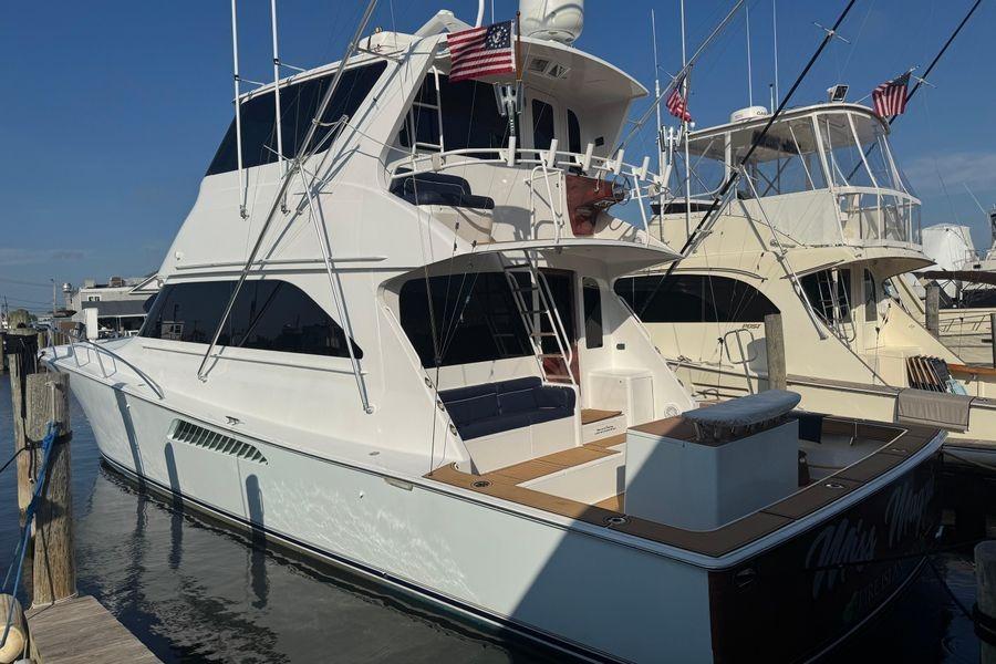 2002 Viking 61 Enclosed Bridge yacht docked at marina, featuring sleek design and American flags.