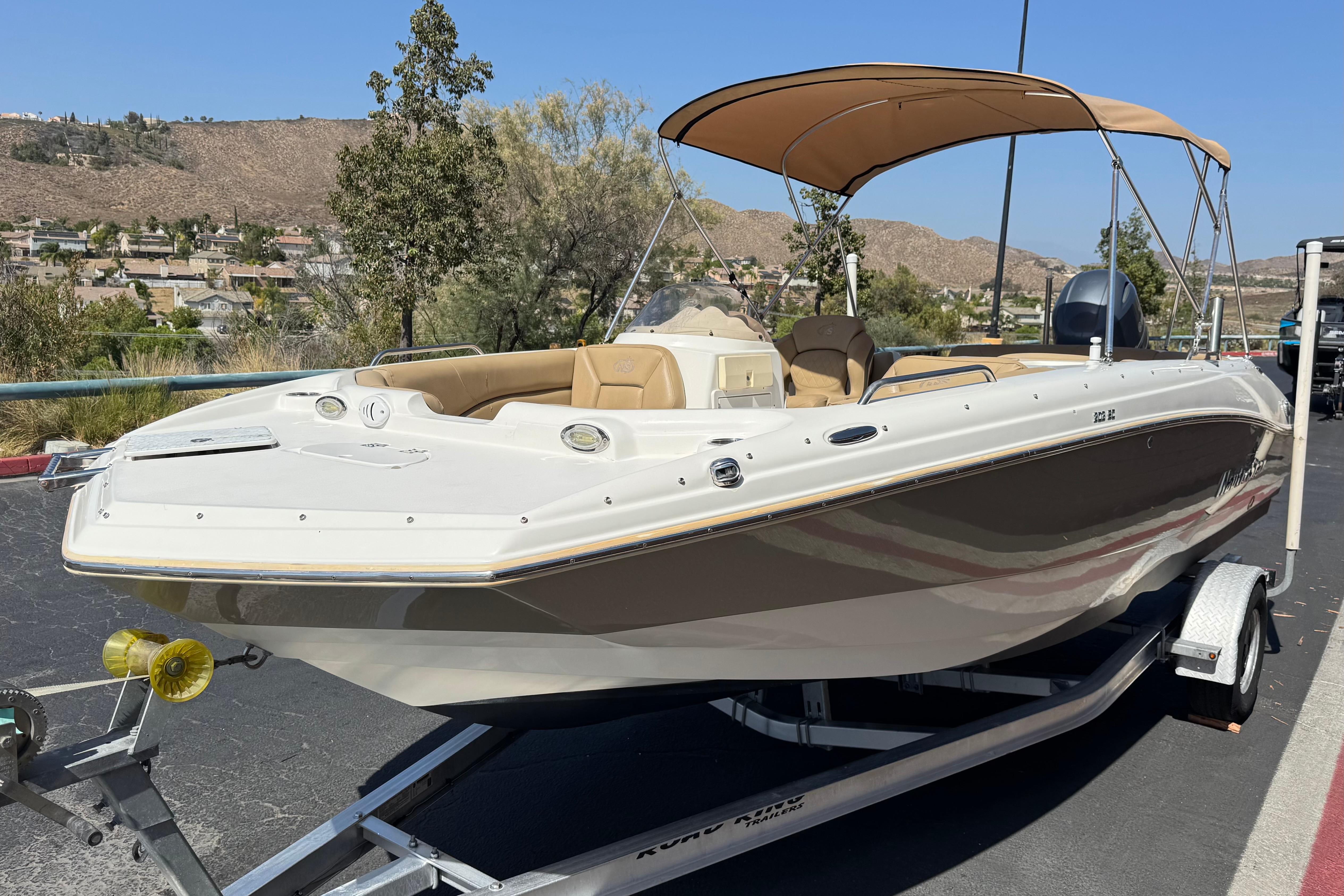 2020 NauticStar 203 SC boat on trailer, beige canopy, parked outdoors.