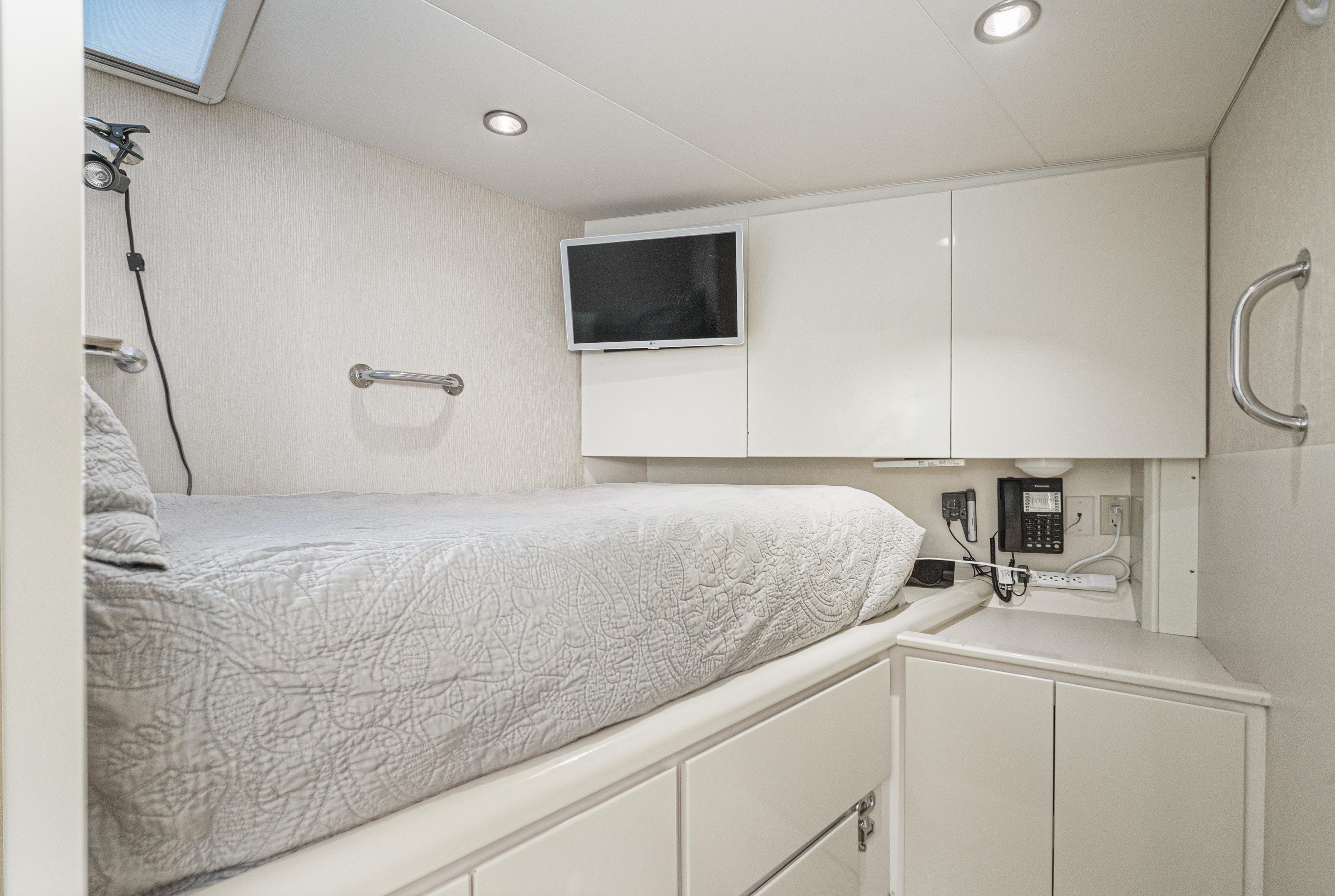 Cozy cabin interior of 1992 Barattucci Yacht Fisher with bed, TV, and storage.
