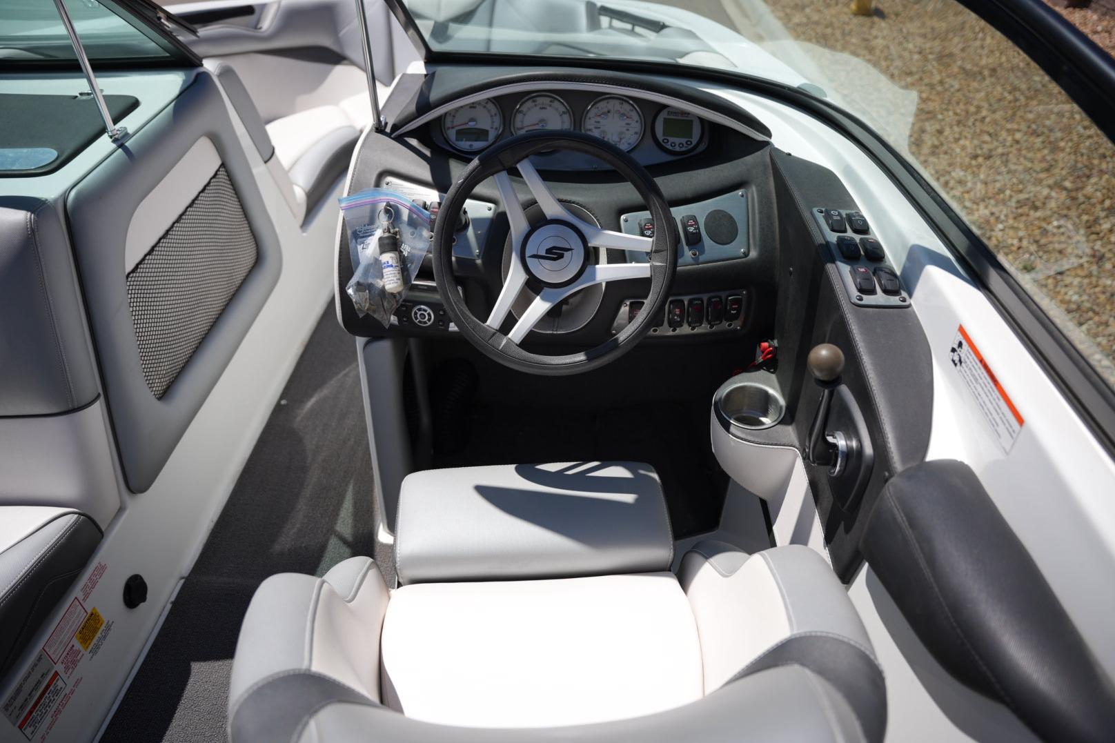 Interior of a 2016 Supreme S211 boat, featuring a sleek steering wheel and control panel.