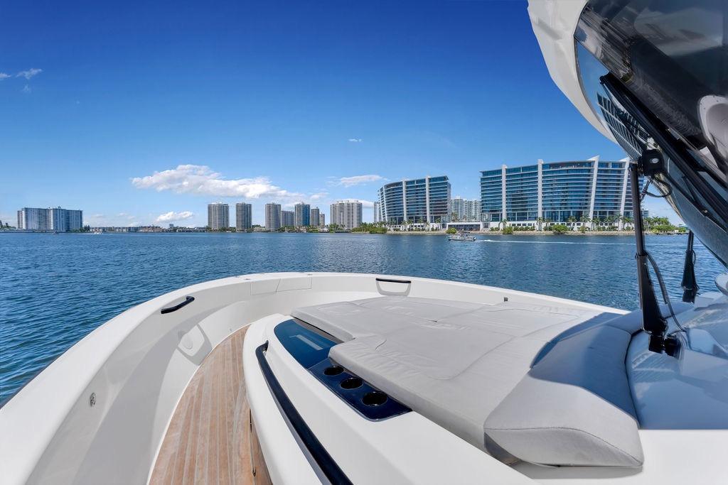 2021 Bluegame BG 42 yacht cruising near modern waterfront buildings under clear blue skies.