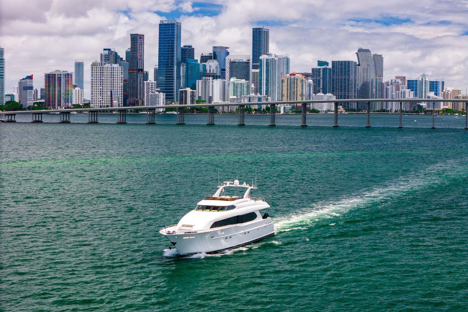 2001 Lazzara Motoryacht cruising near a city skyline with a bridge in the background.