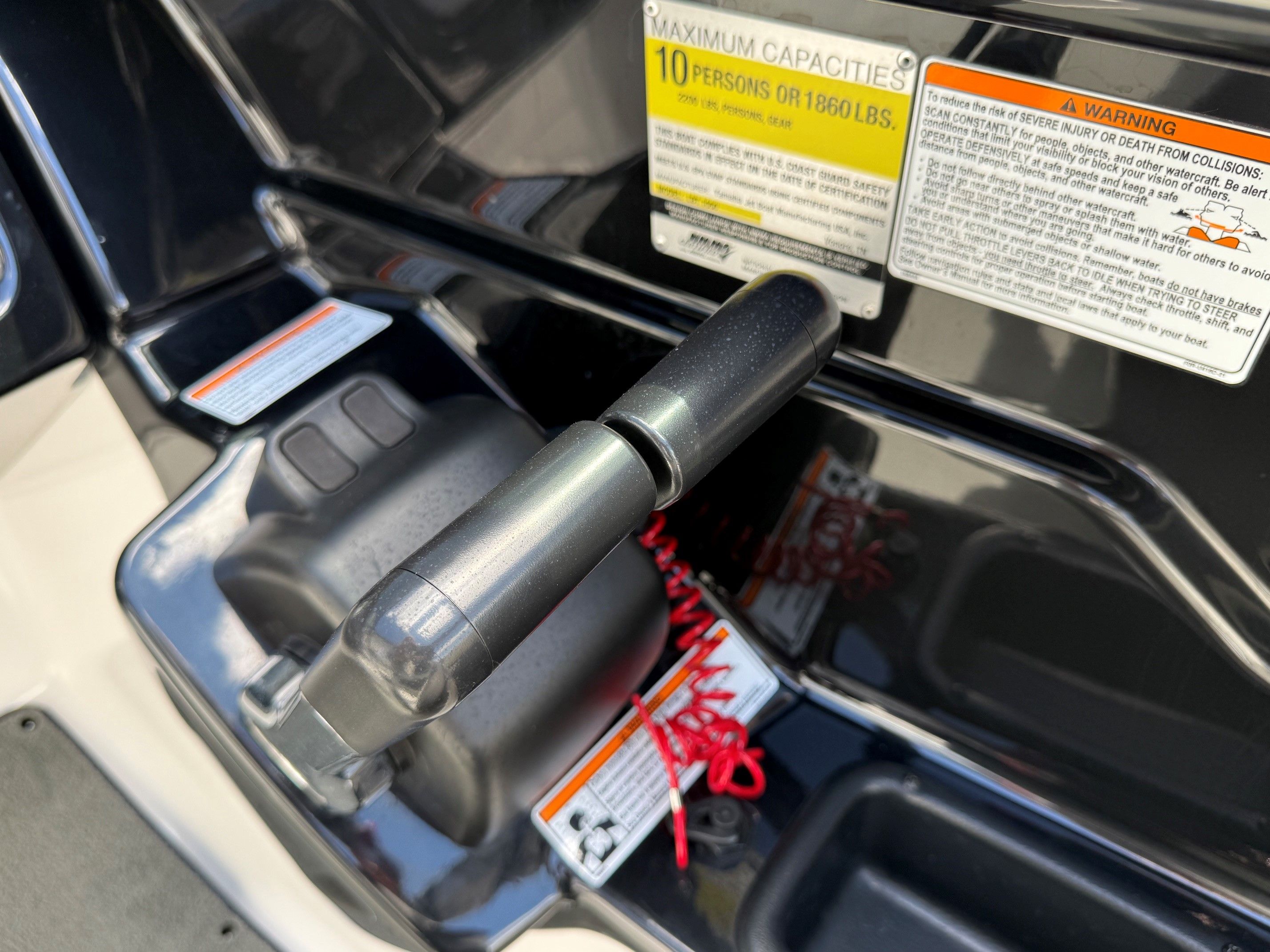 Close-up of a Yamaha SX210 boat throttle lever with warning labels.