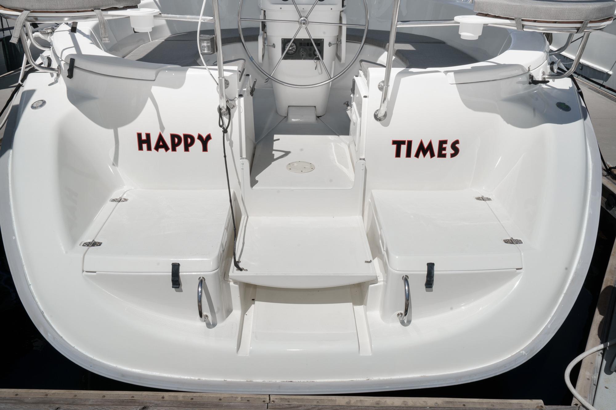 1996 Hunter 376 sailboat stern with "Happy Times" text, docked in marina.