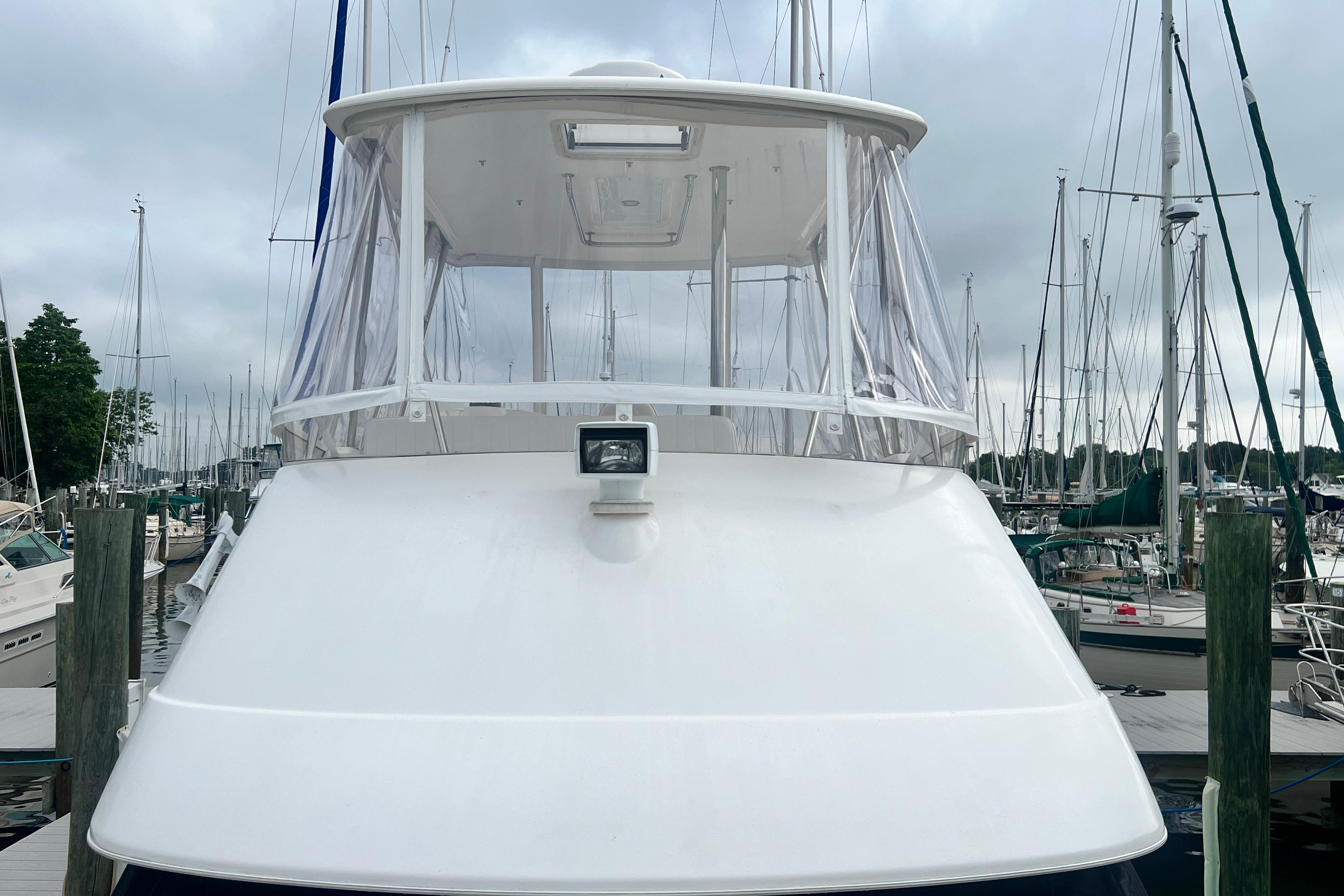 2007 Riviera 33 Flybridge yacht docked at a marina, surrounded by sailboats.