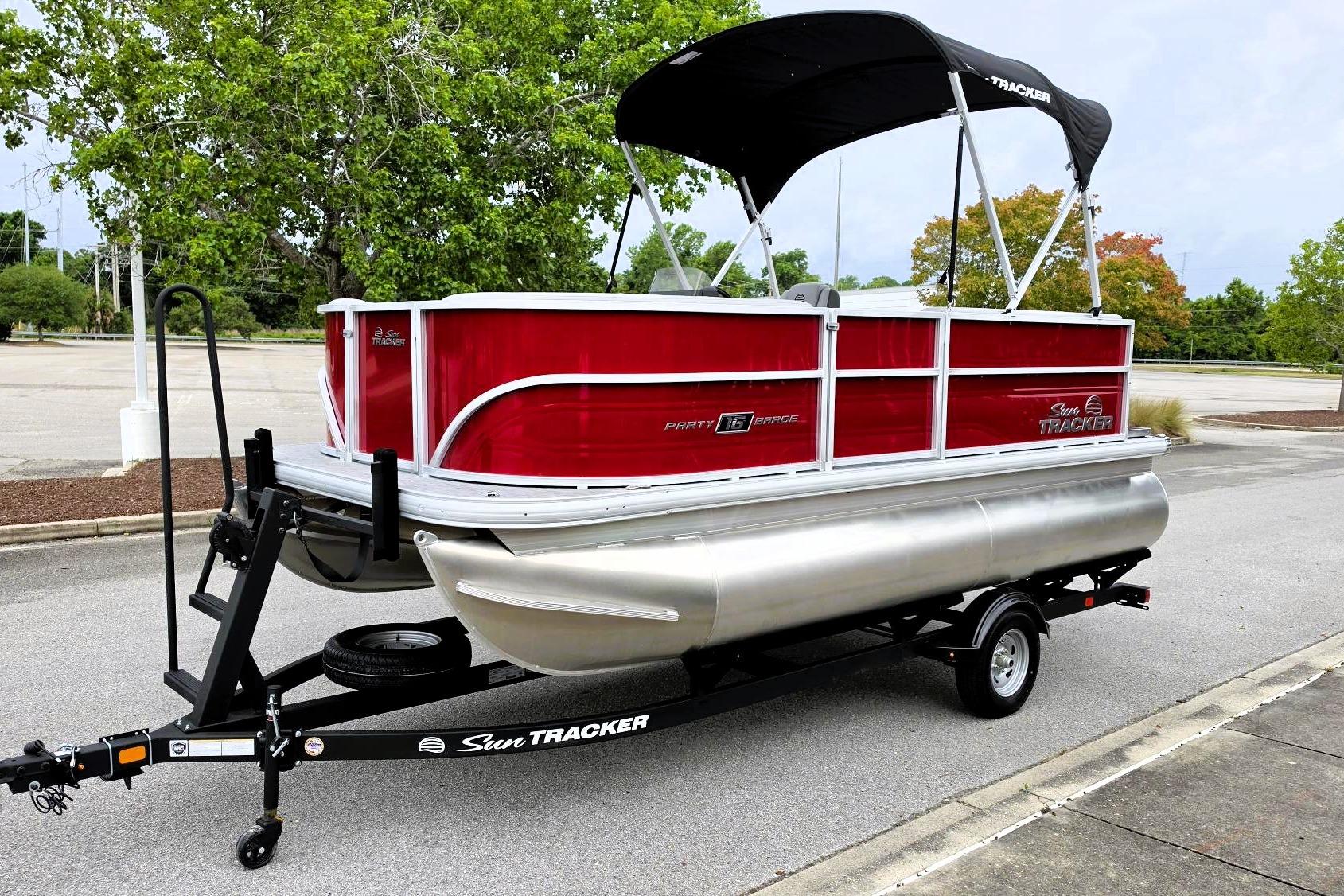 2026 Sun Tracker Party Barge 16 DLX pontoon boat on trailer in parking lot.