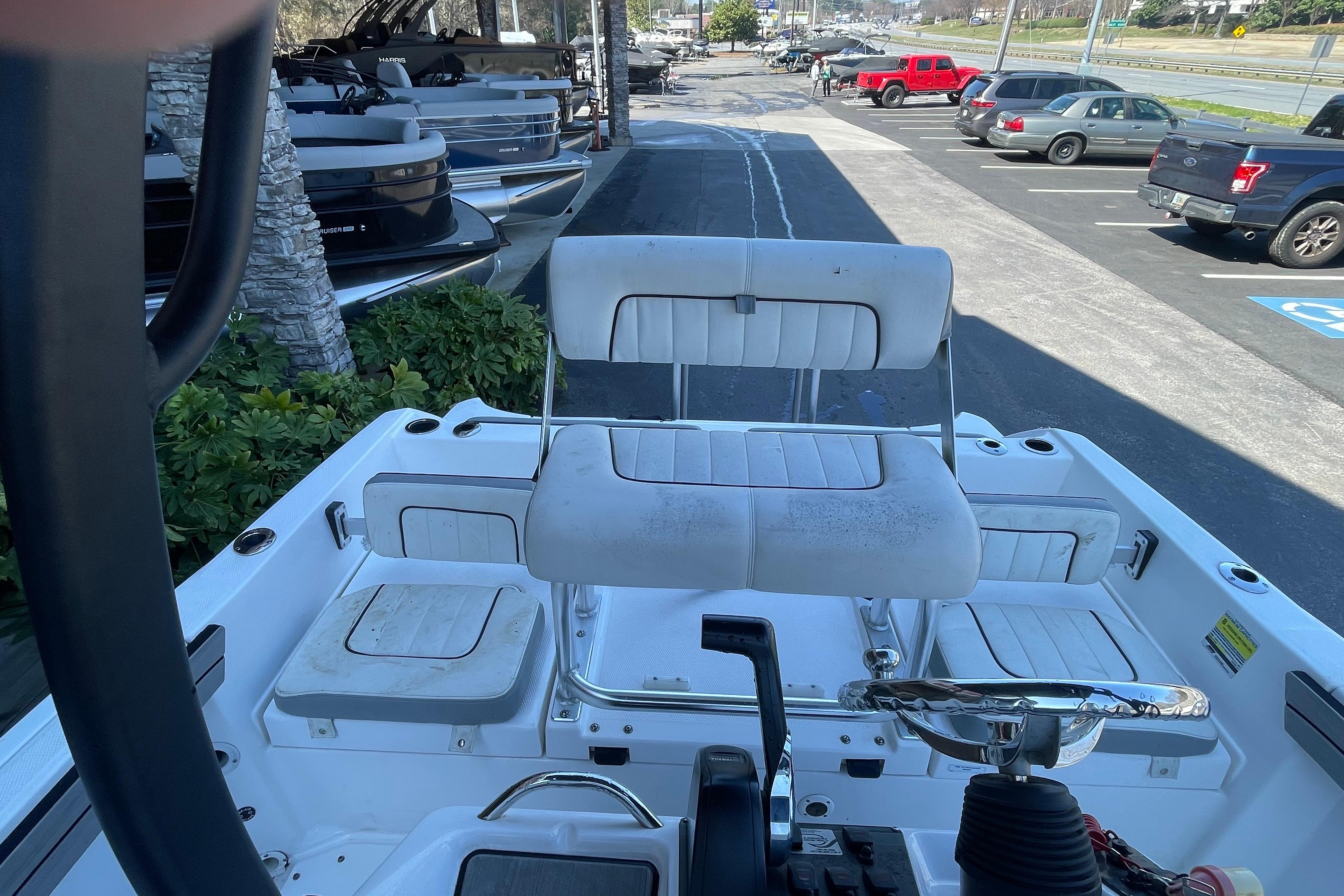 2021 Yamaha Boats 195 FSH Sport interior with seating and steering wheel, parked outdoors.