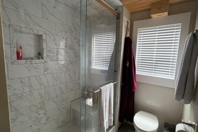 Modern bathroom in 1997 Stardust Houseboat with marble tiles and glass shower enclosure.