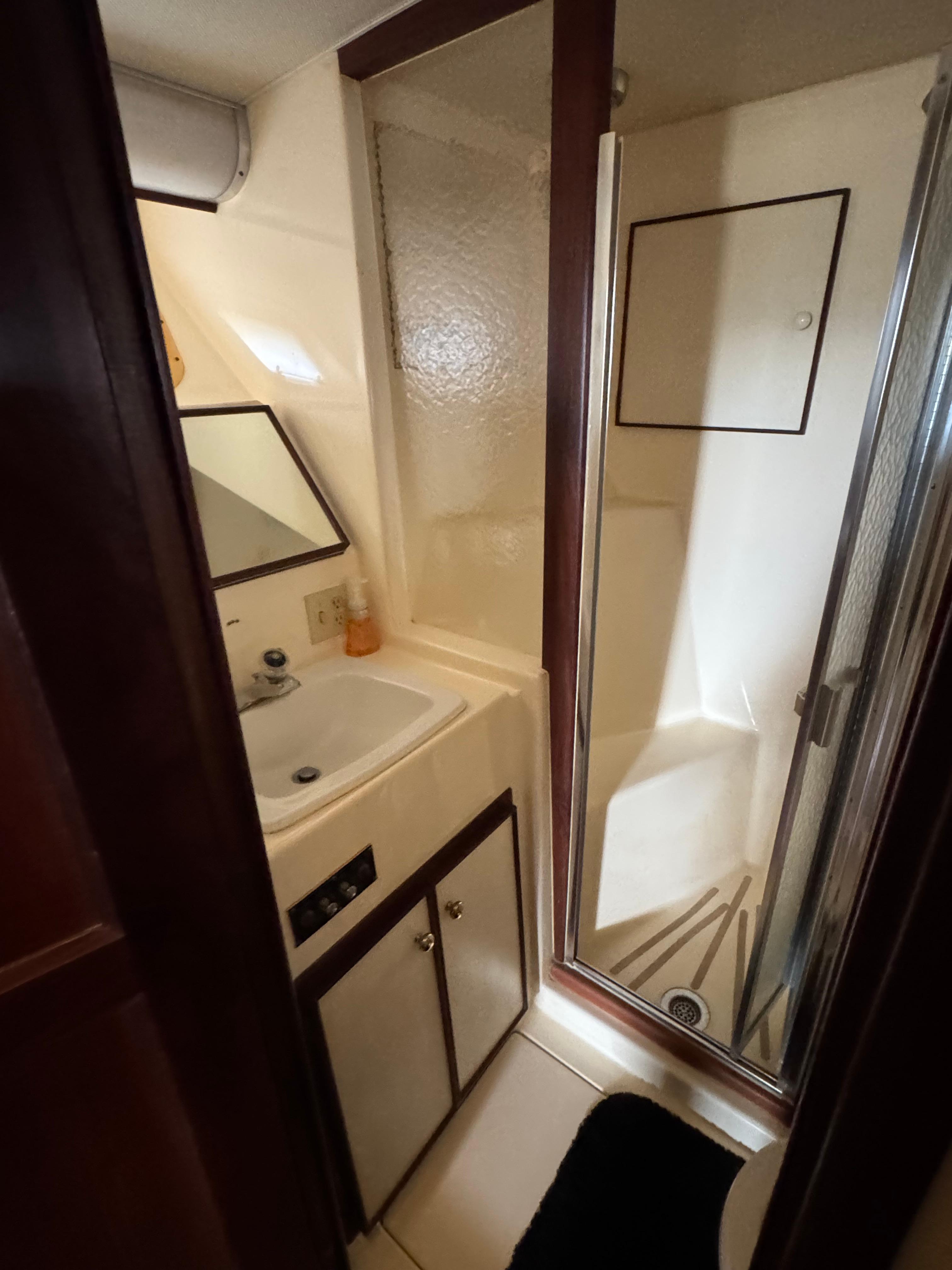 1984 Hatteras 46 Convertible yacht bathroom with sink, mirror, and shower.