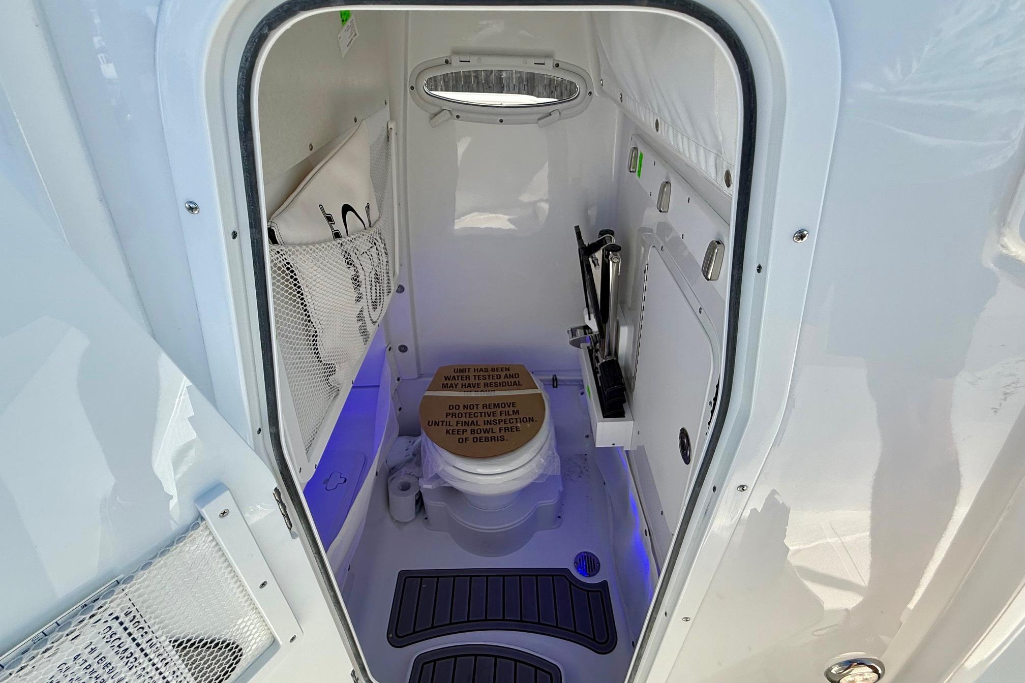2026 Sea Hunt Ultra 255 SE boat interior with compact marine toilet and storage.