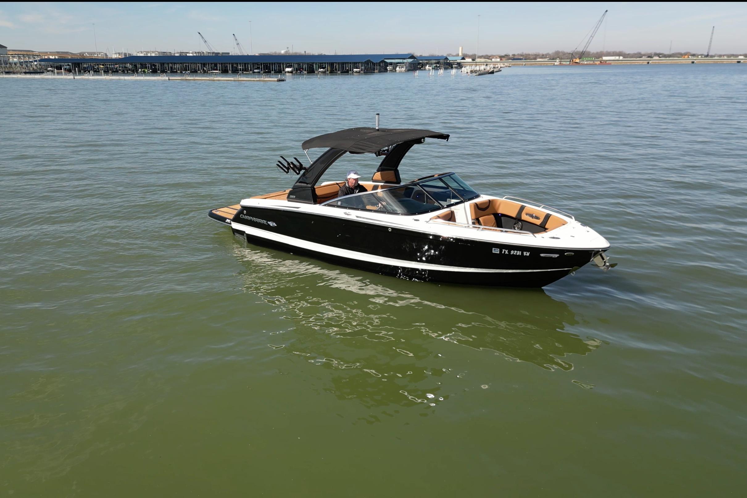 2023 Chaparral 26 Surf boat on calm water, featuring sleek black and white design.