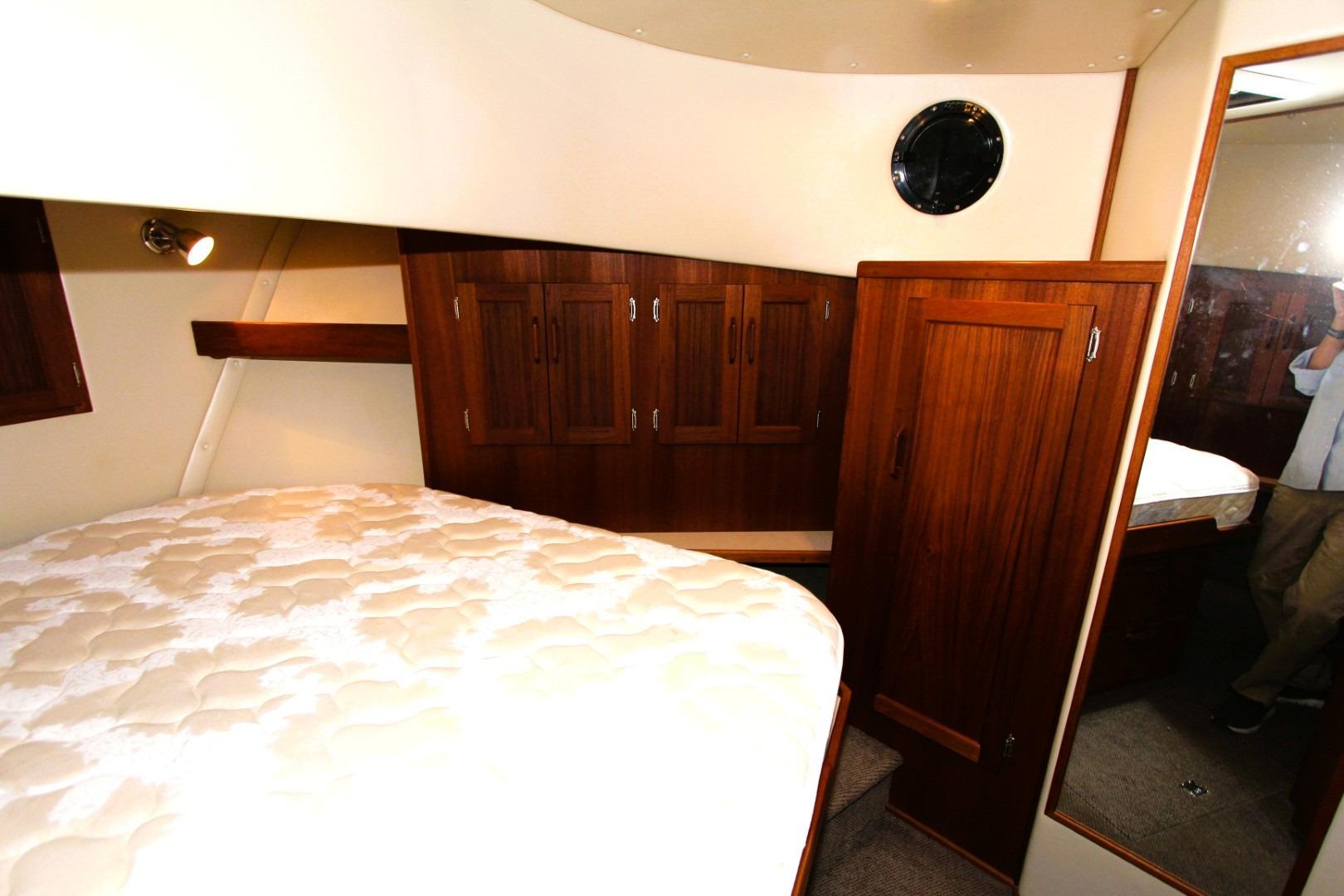 Cozy cabin interior of a 2002 Nordic Tug 37 with wood cabinetry and a comfortable bed.