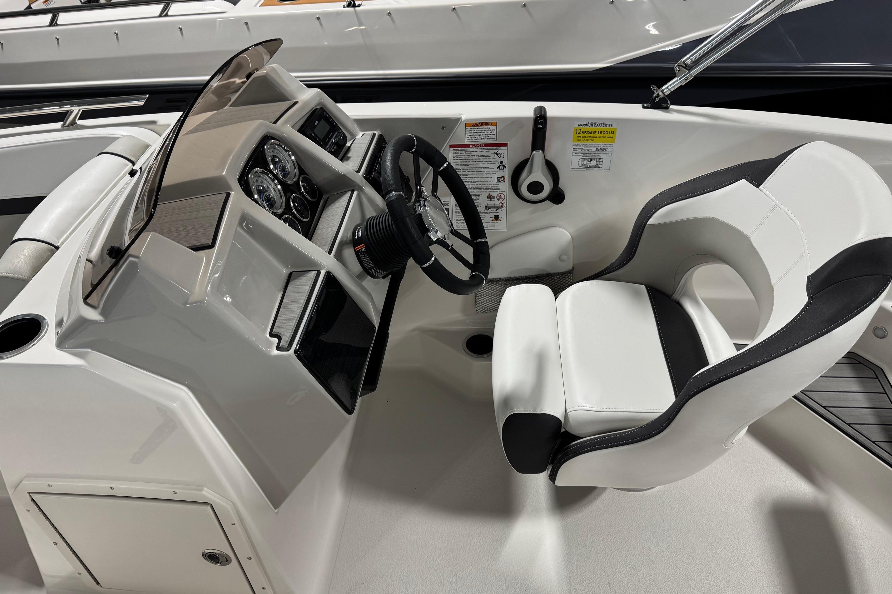 2026 Starcraft SVX 191 OB boat cockpit with steering wheel and white captain's chair.