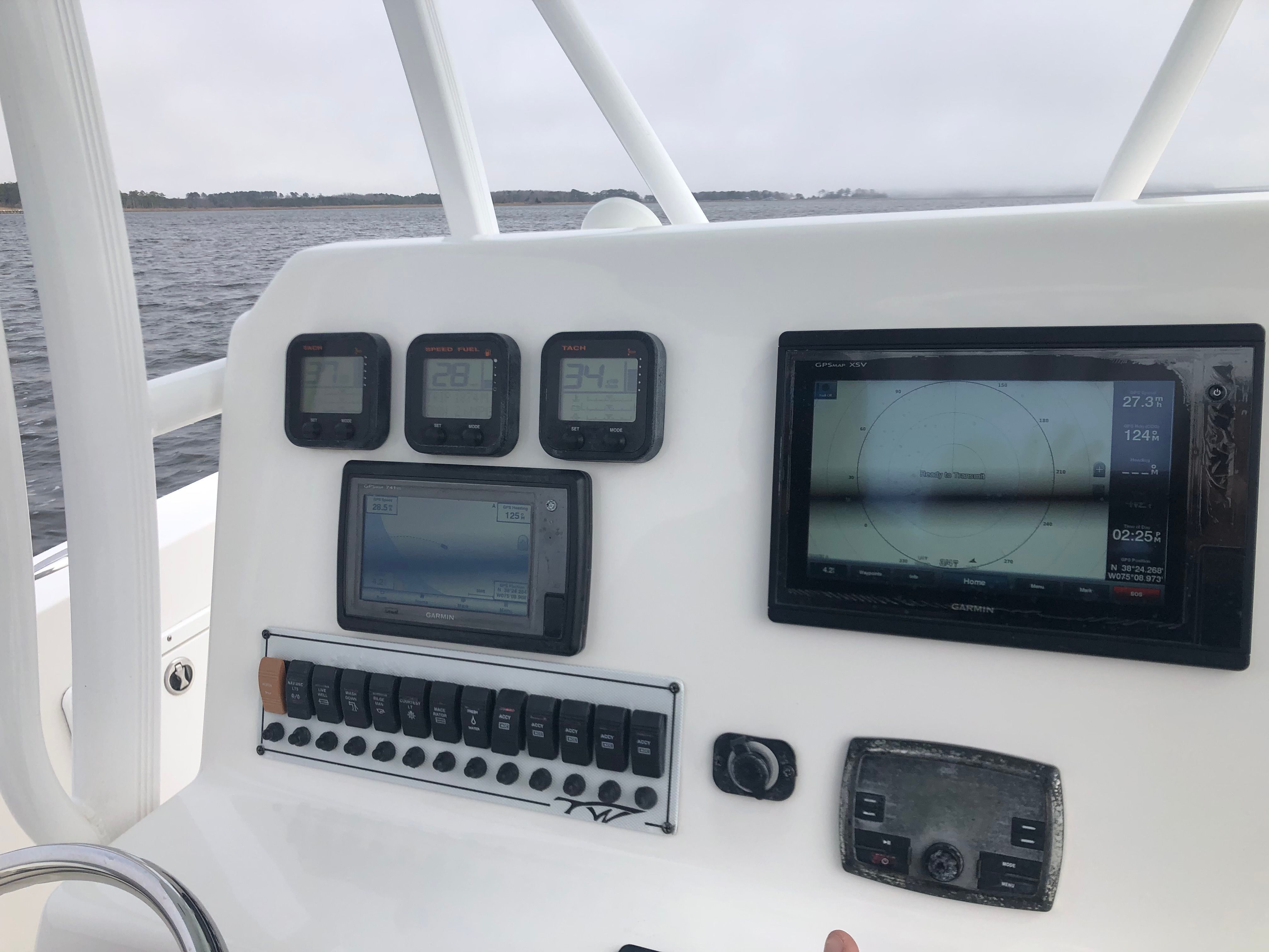 The image shows the dashboard of a 2015 Tidewater 250 Adventure boat with multiple screens and switches.
