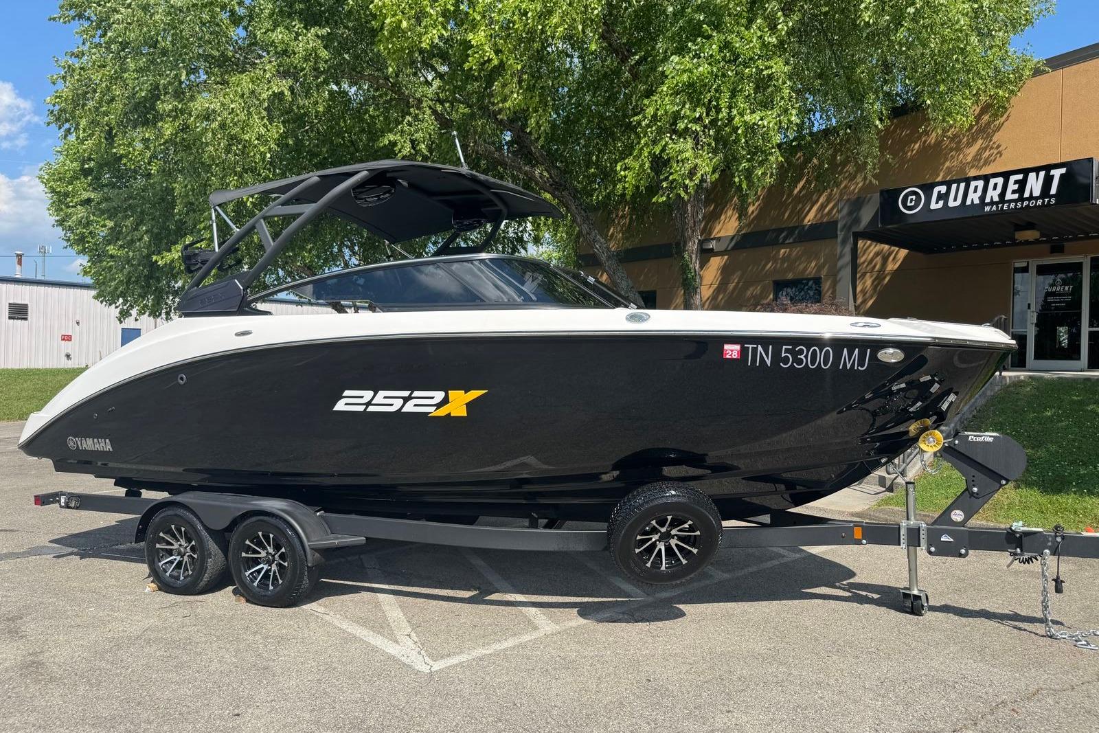 2023 Yamaha Boats 252XE in black, parked on a trailer outside a watersports store.