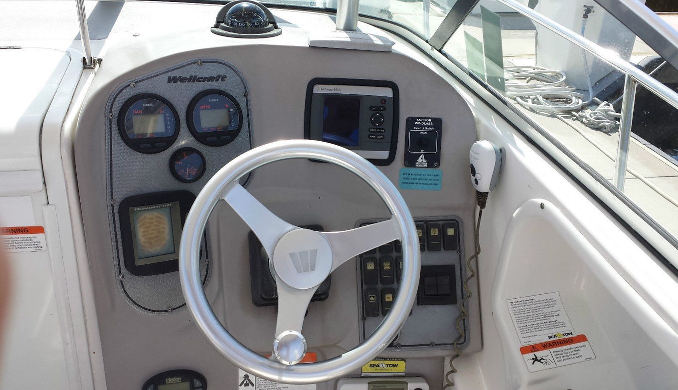 The image shows the helm of a 2006 Wellcraft 252 Coastal boat with instruments and a steering wheel.