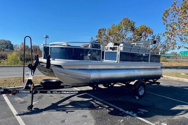 2026 Sun Tracker Bass Buggy 18 DLX pontoon boat on trailer in parking lot.