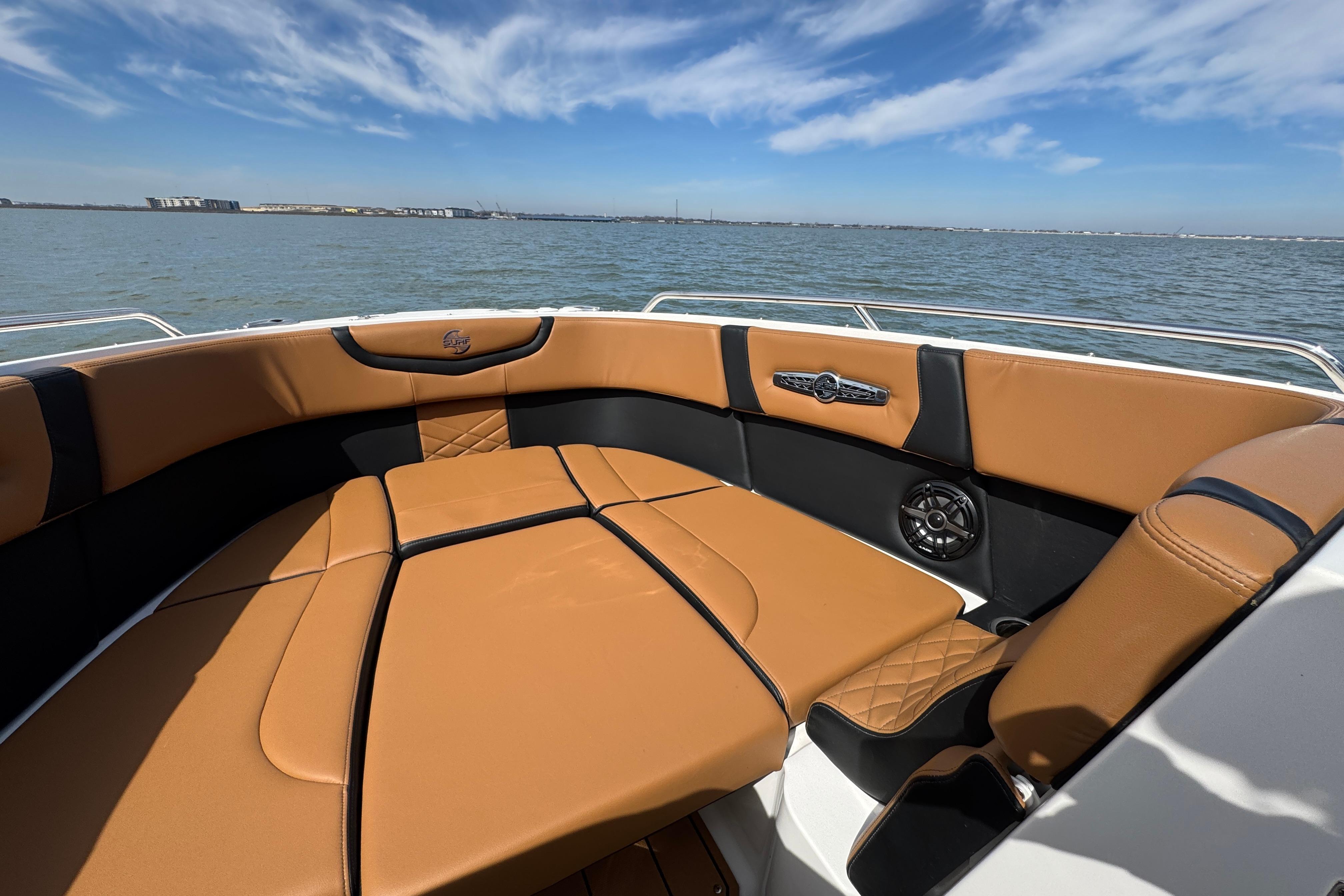 2023 Chaparral 26 Surf boat interior with tan seating, on a sunny day at sea.