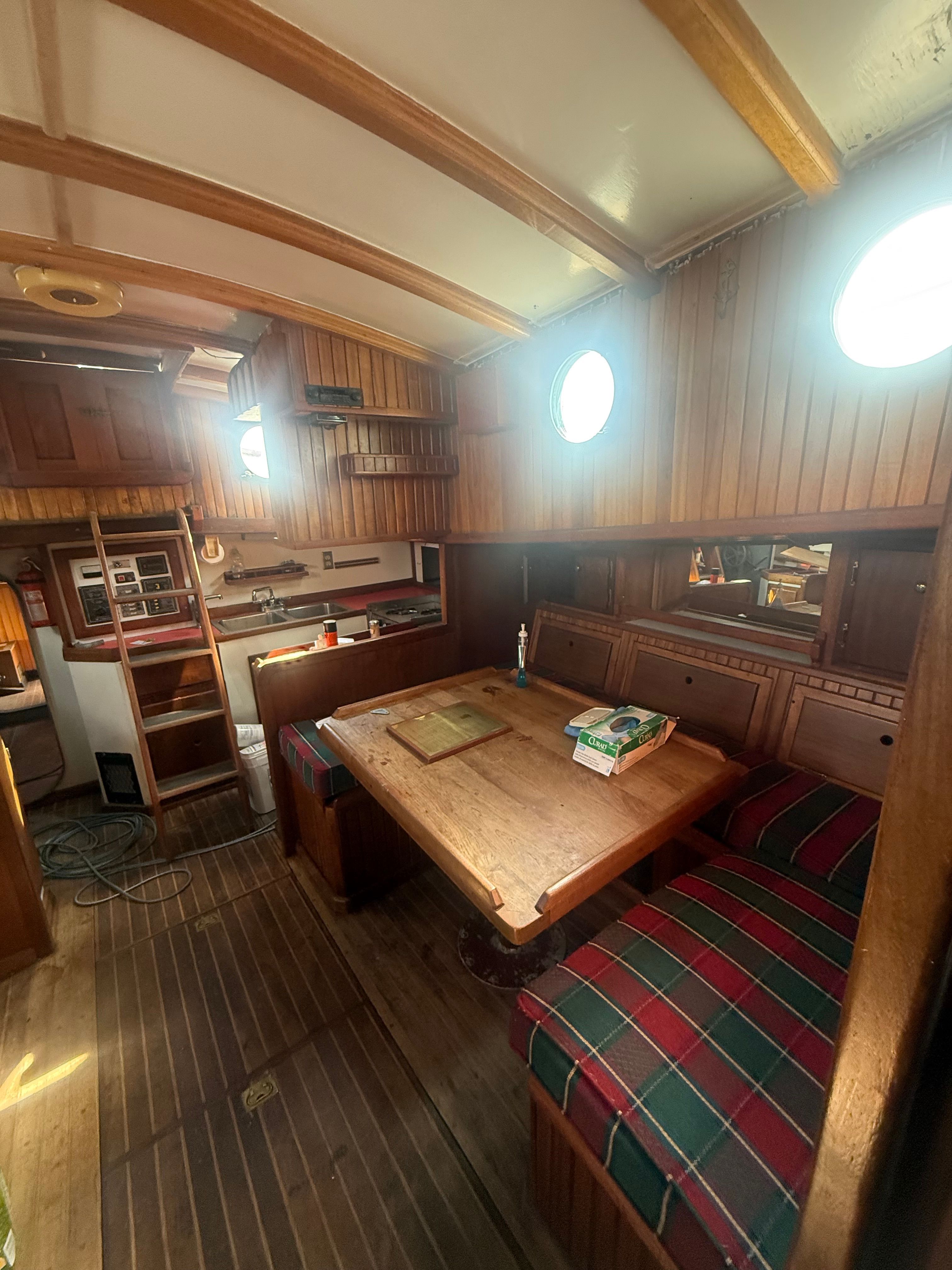 Interior of a classic sailboat with wooden features and a cozy seating area.