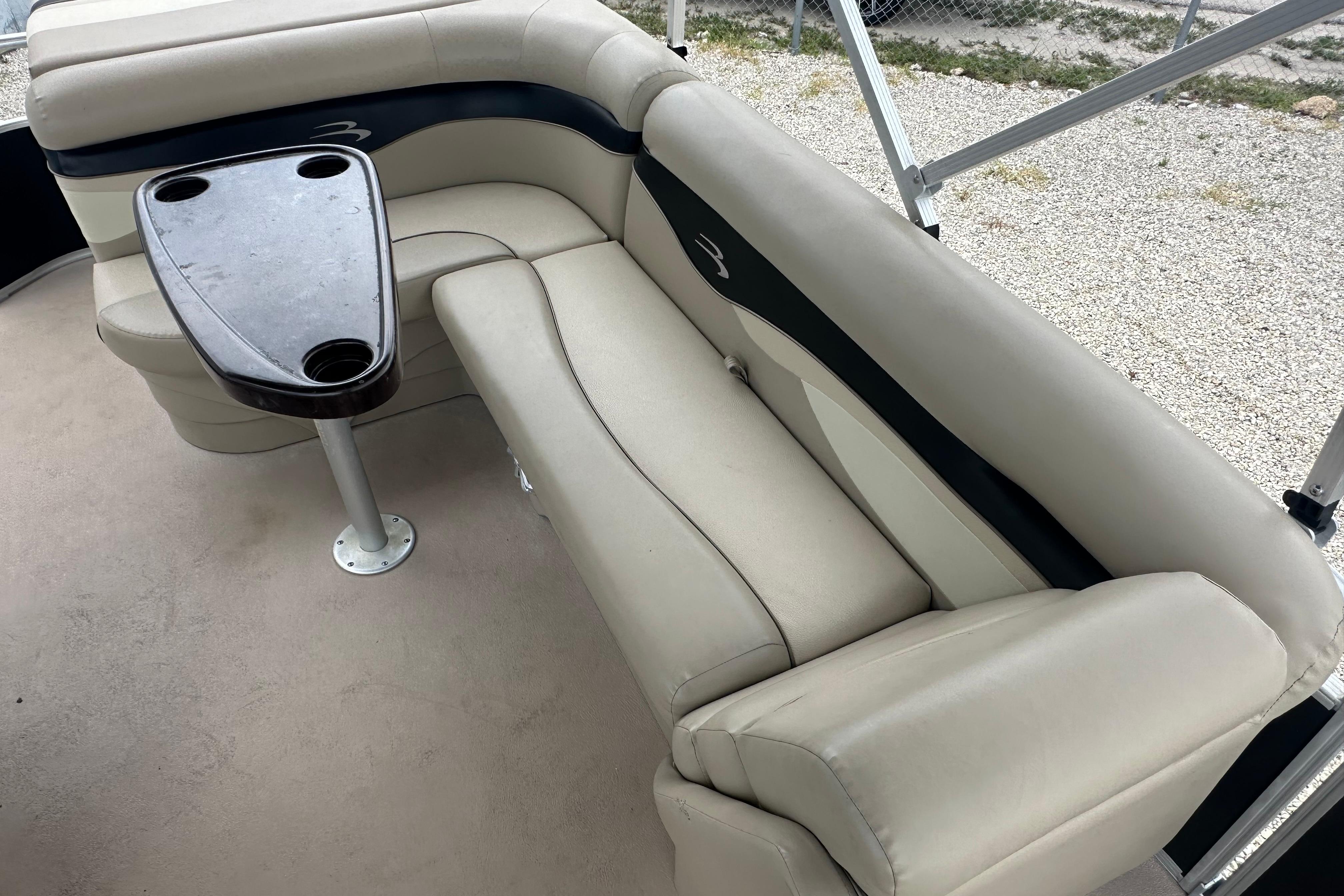 2014 Bennington S22 boat interior with beige seating and a small table.