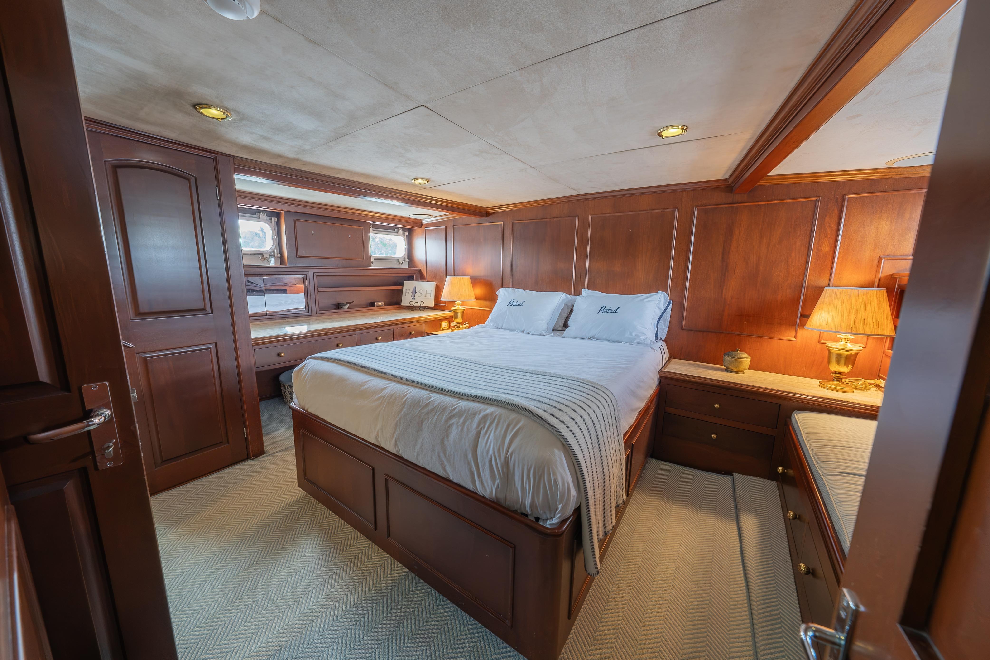Luxurious 1963 Trumpy Classic yacht bedroom with elegant wood paneling and cozy lighting.