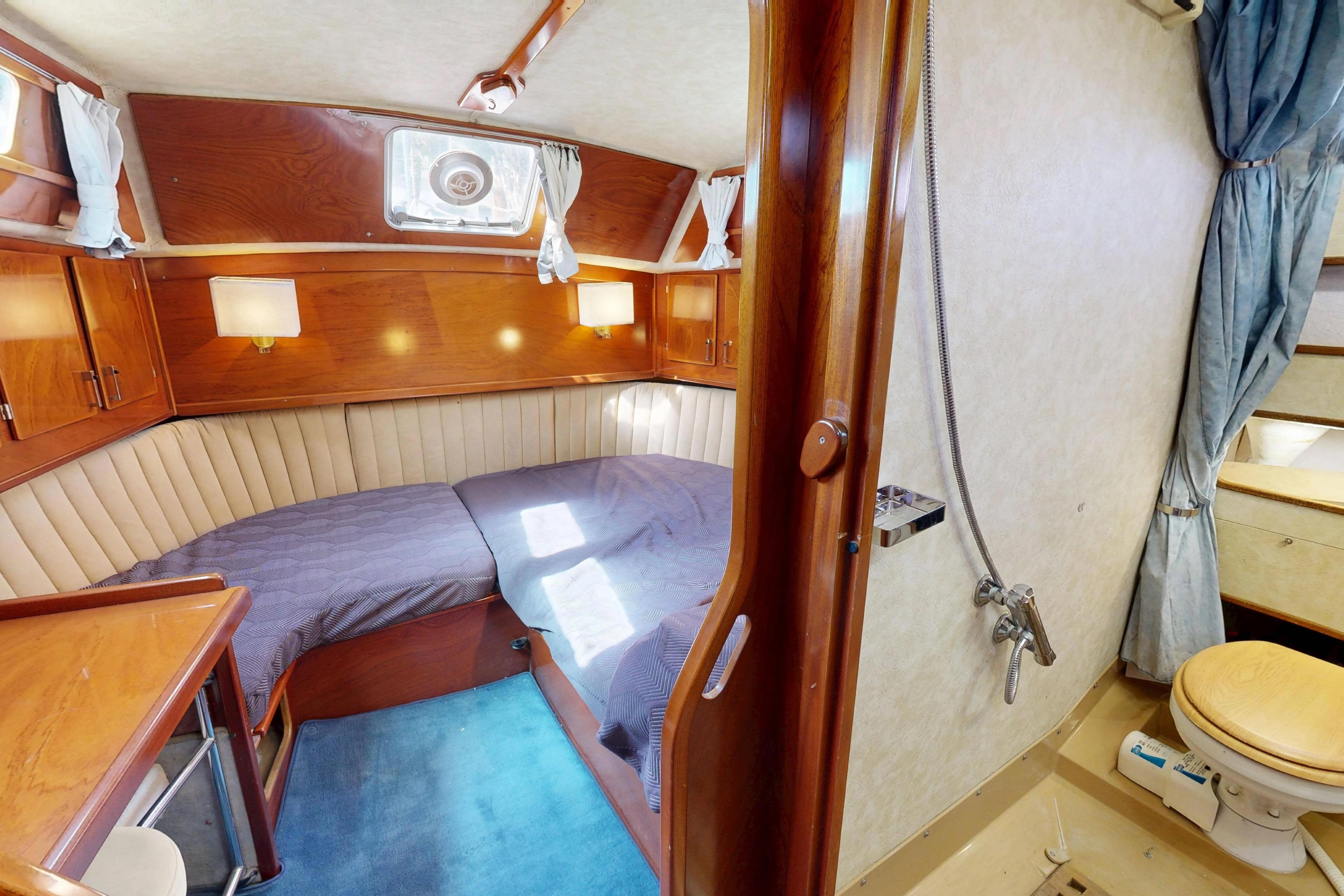 Cozy cabin interior of 1999 Amel Super Maramu 2000 yacht with wood paneling and seating.