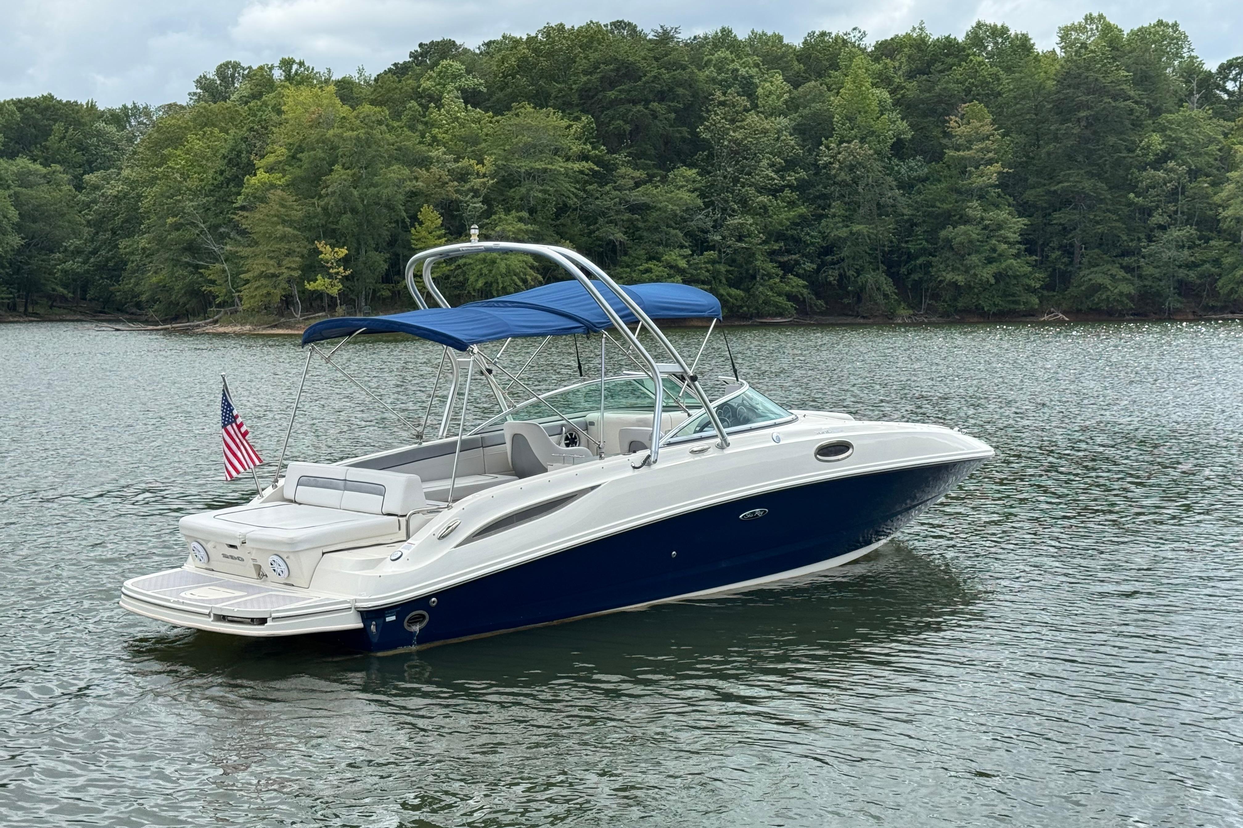 2009 Sea Ray 280 Sundeck boat on a serene lake with lush green trees.