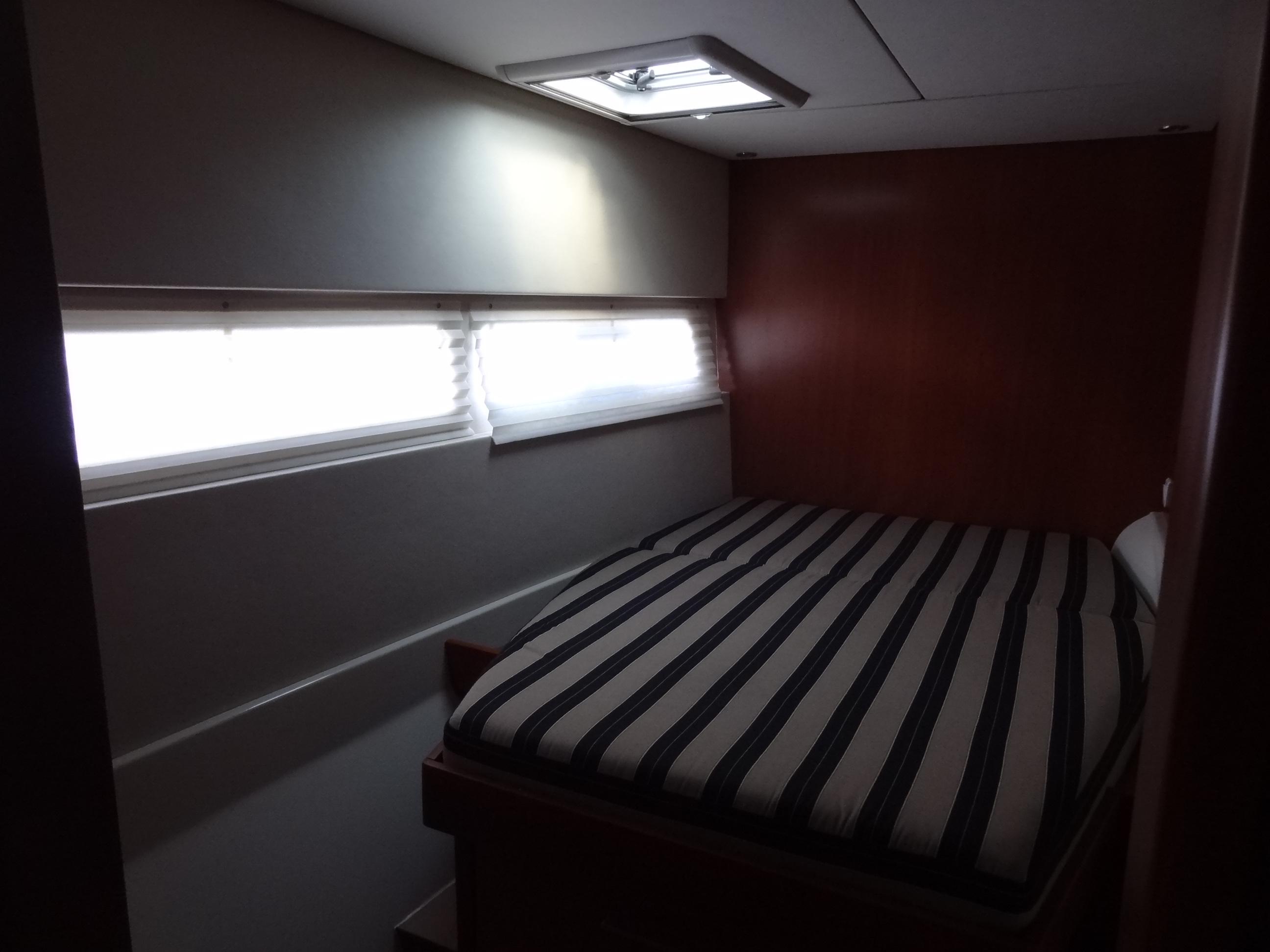 2014 Leopard 58 yacht interior bedroom with striped bedding and natural light.