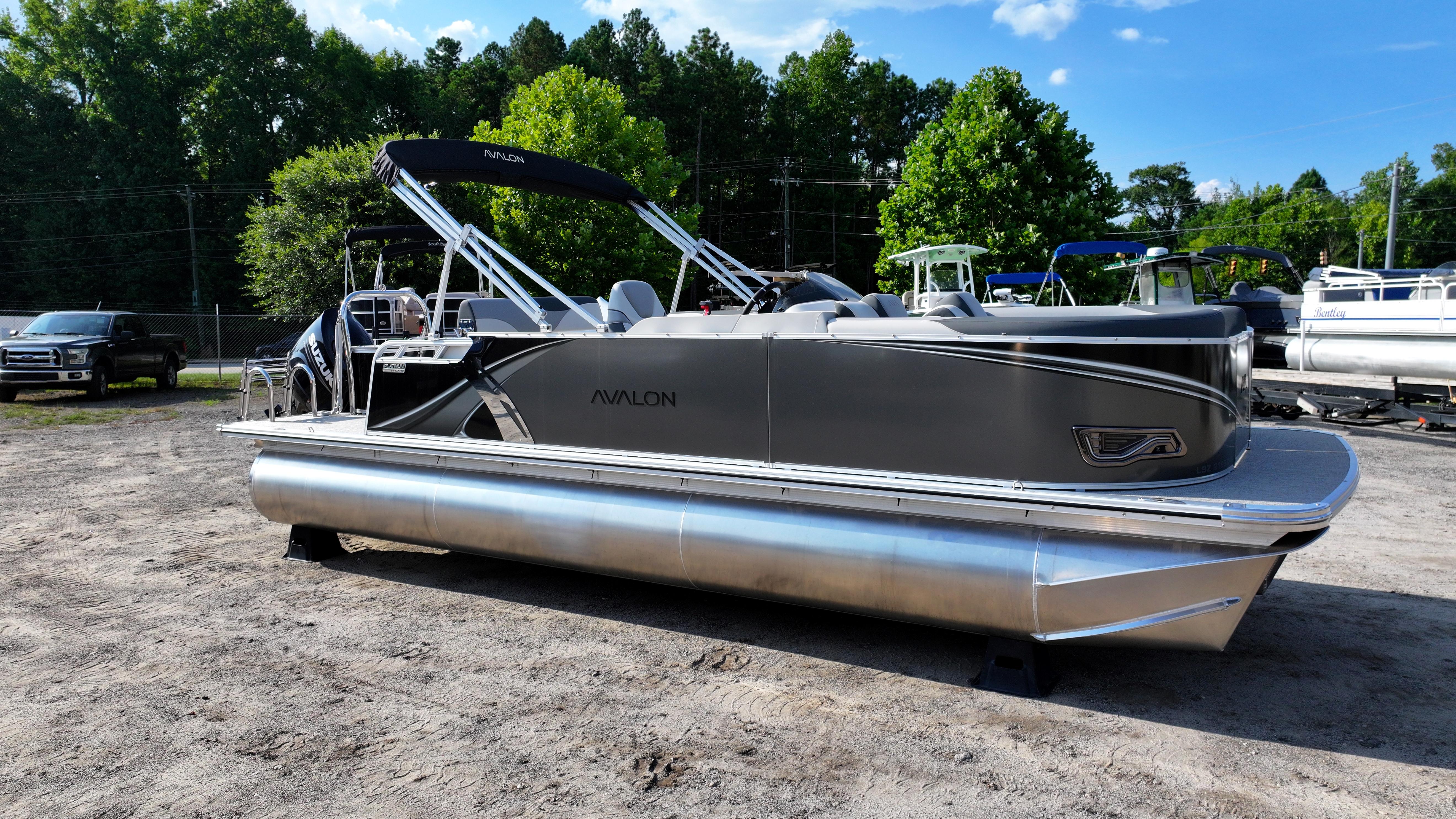 2025 Avalon LSZ Cruise Rear Bench pontoon boat parked outdoors.