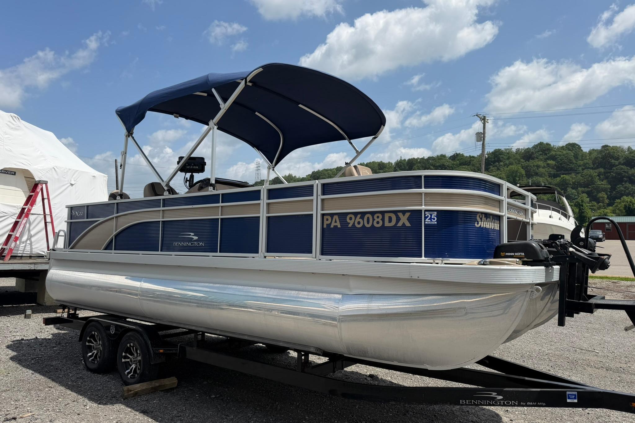 2020 Bennington SX 22 SFX pontoon boat with canopy on trailer, under clear sky.
