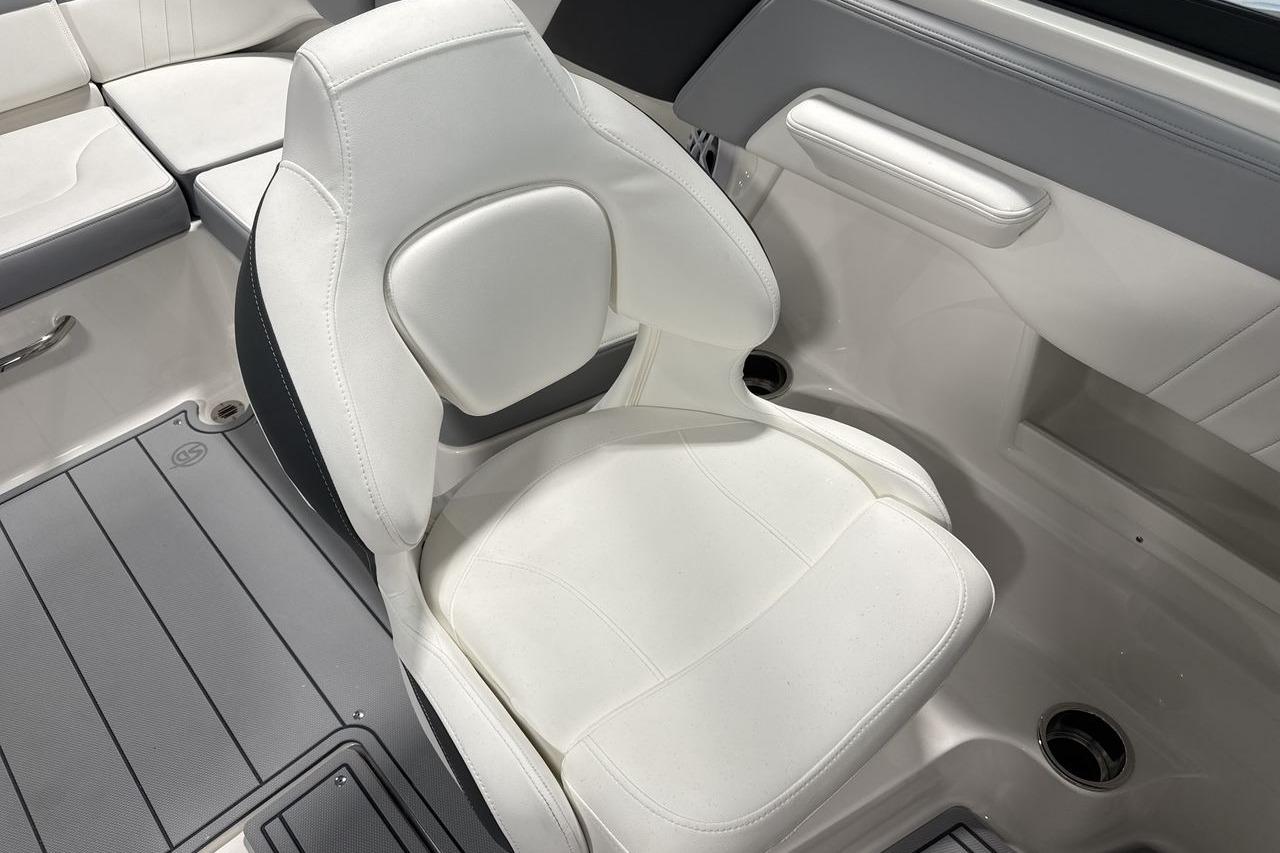 A white cushioned boat seat with gray flooring and cup holders.