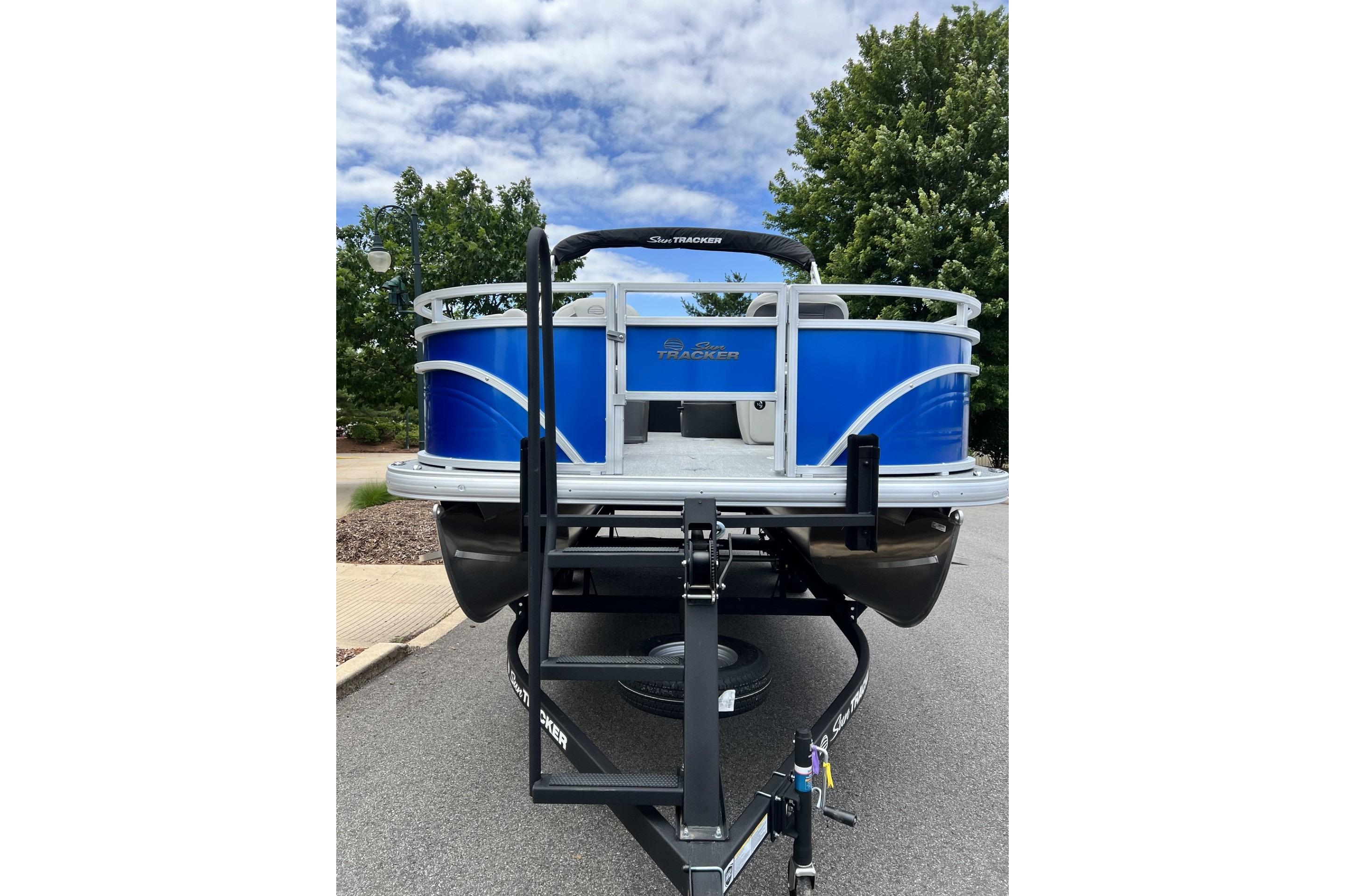 2026 Sun Tracker Fishin' Barge 20 DLX pontoon boat on trailer, parked outdoors.