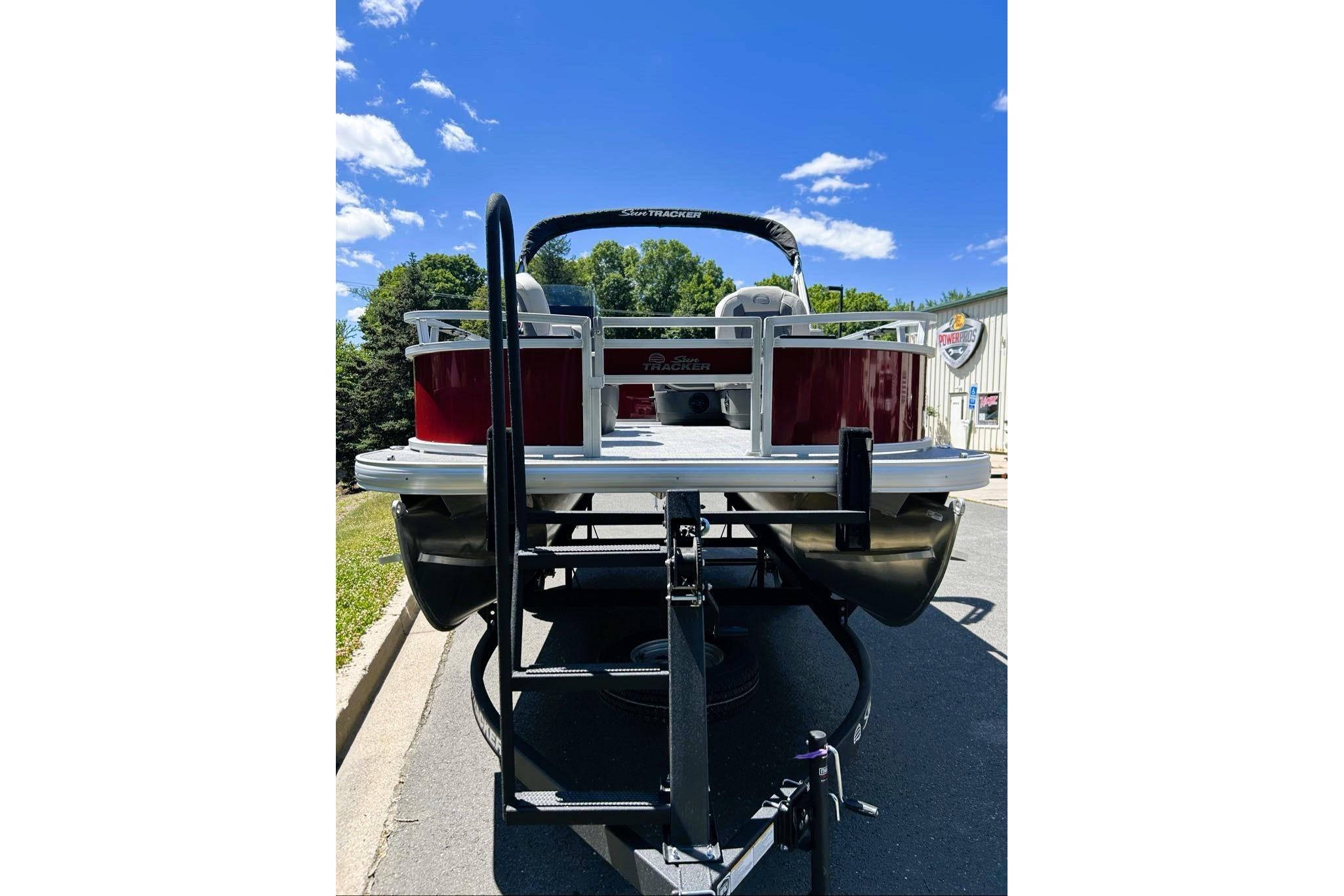 2026 Sun Tracker Bass Buggy 16 XL Select pontoon boat on trailer, sunny day.