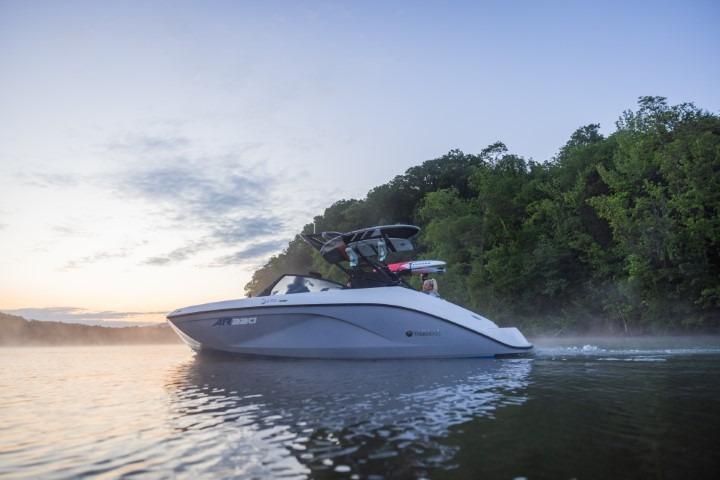 2026 Yamaha Boats AR220 cruising on a serene lake at sunset.