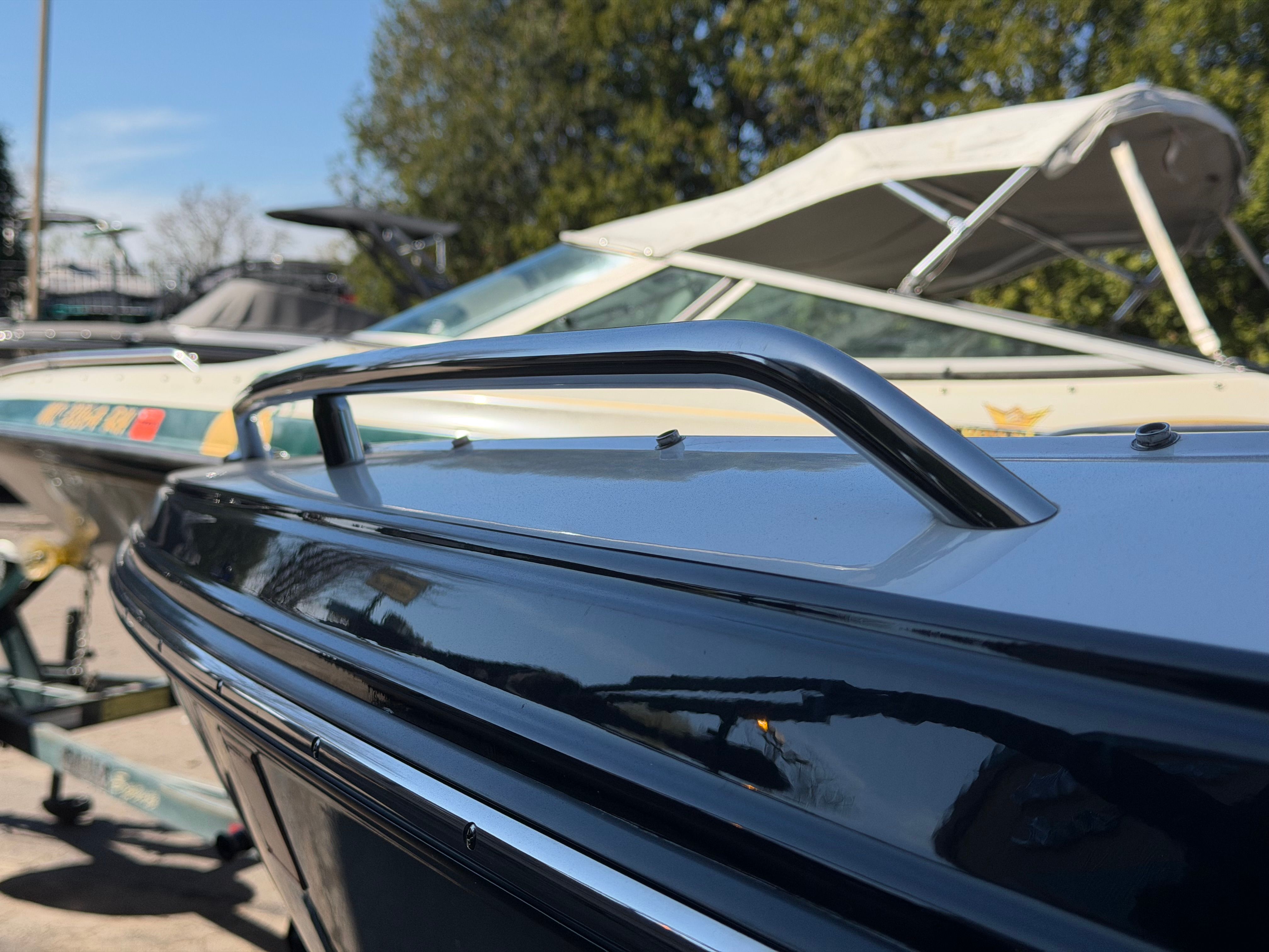 Close-up of a blue boat with stainless steel handrail, parked outdoors.