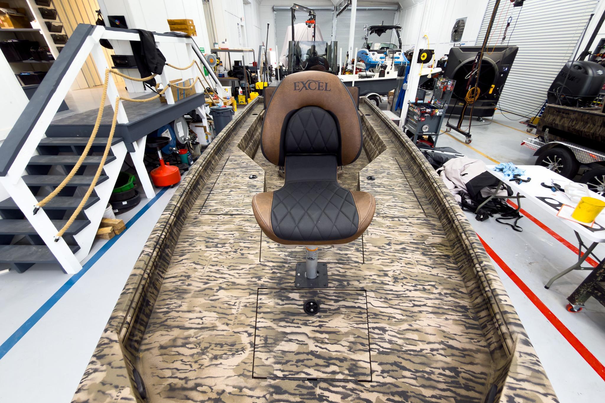 2026 Excel 220 Bay Pro Elite boat interior with camo design and central seat in workshop.