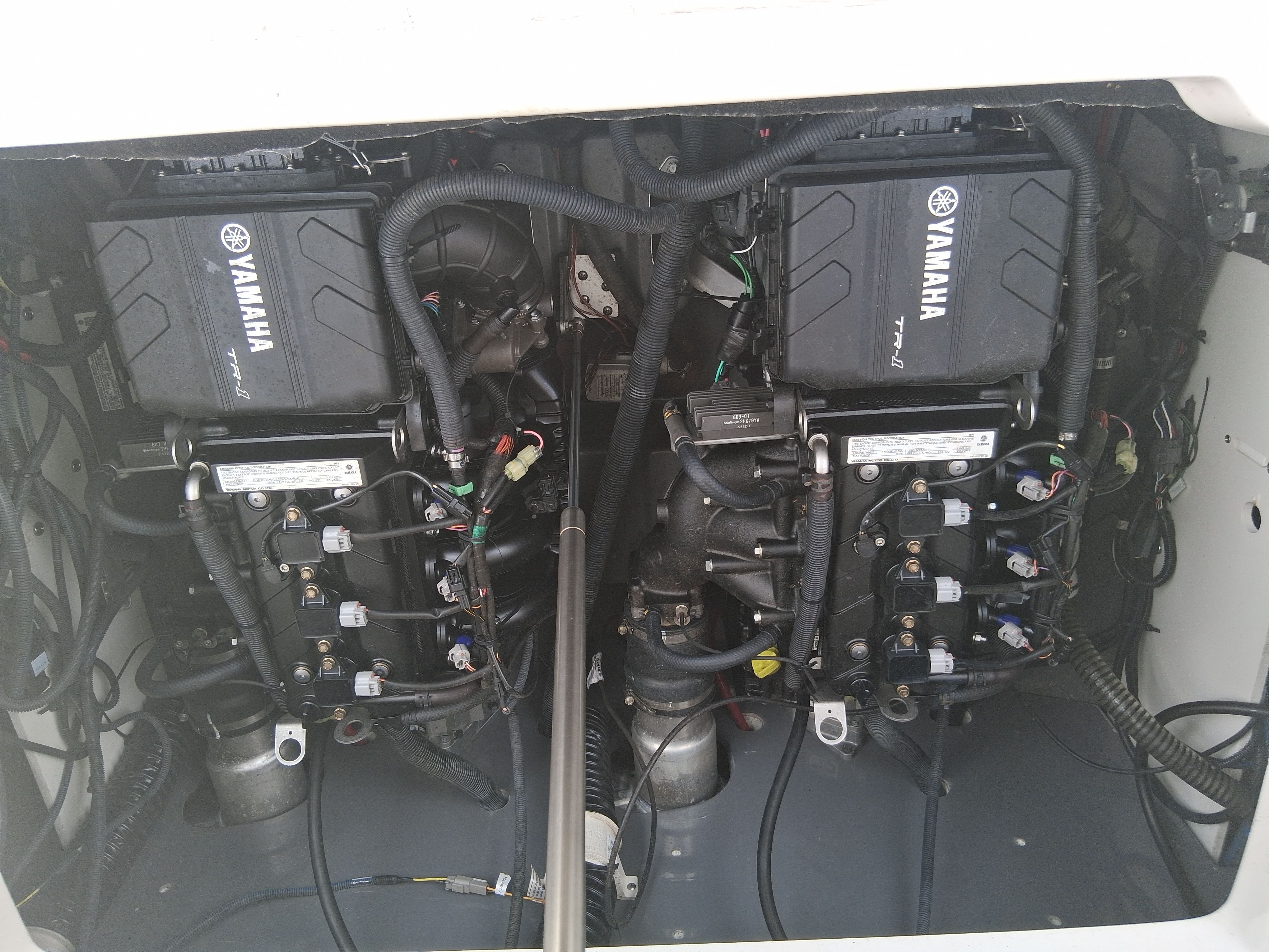 The engine compartment of a Yamaha 220 FSH Sport boat with two engines and wiring.