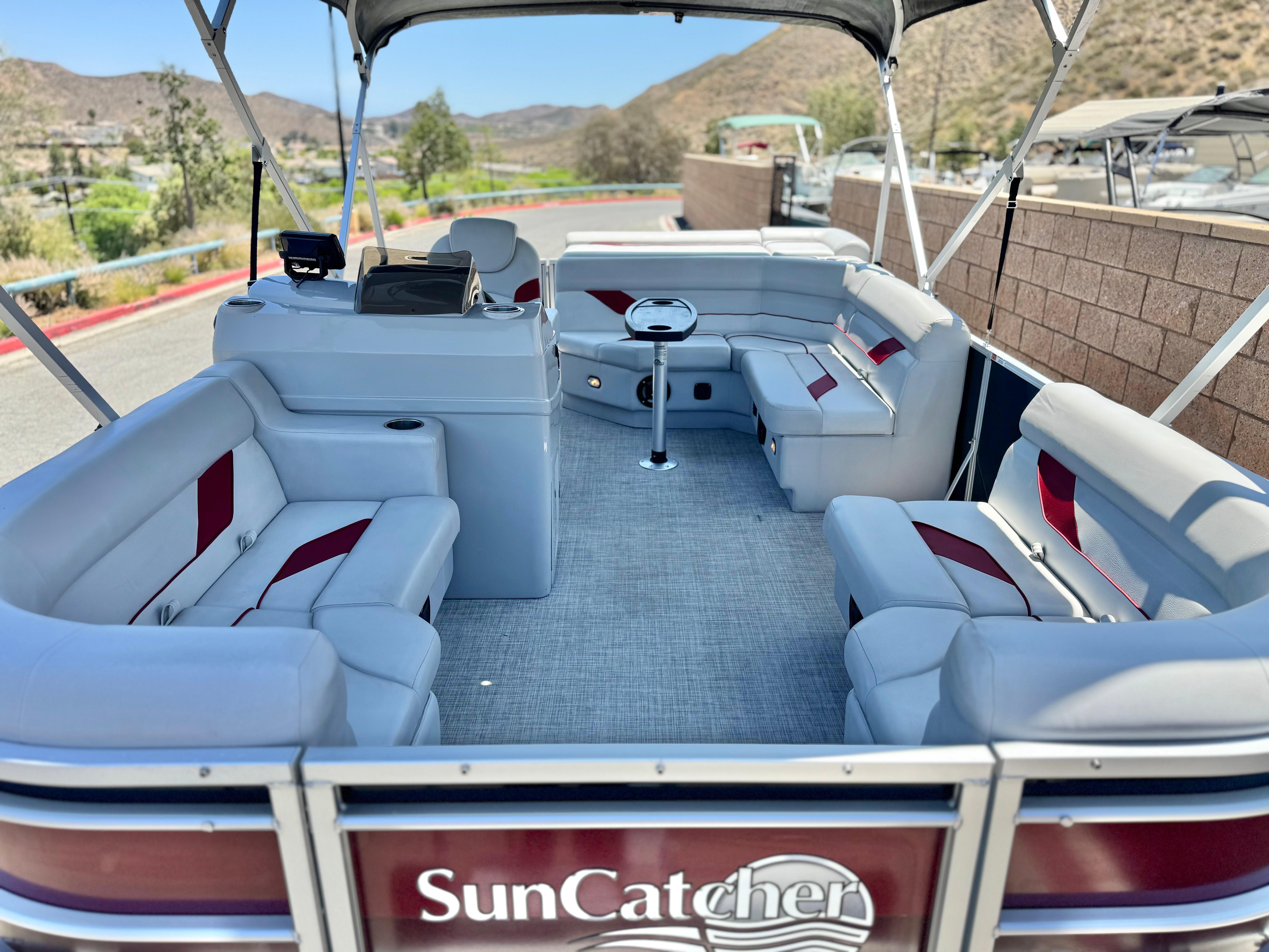 2021 SunCatcher Select 18C pontoon boat with spacious seating and scenic background.