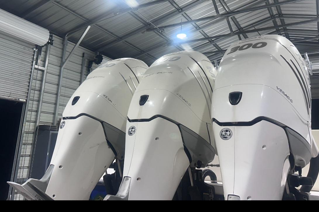 Three powerful outboard motors on a 2005 Contender 35 ST boat in a garage.